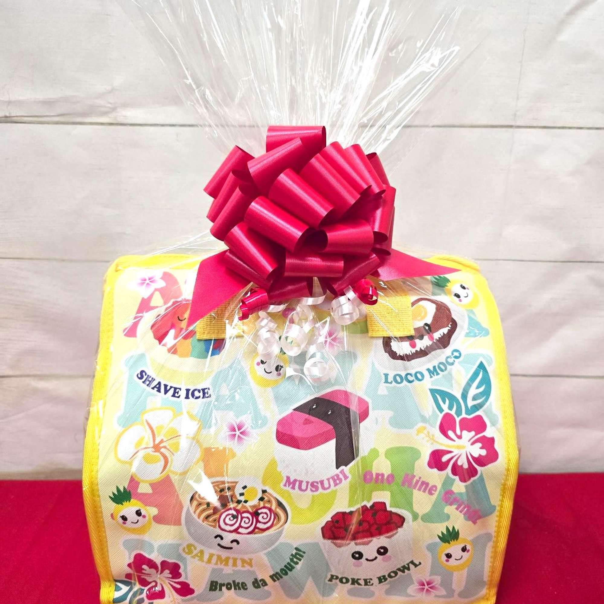 Colorful tote bag wrapped in cellophane with a large red bow on top