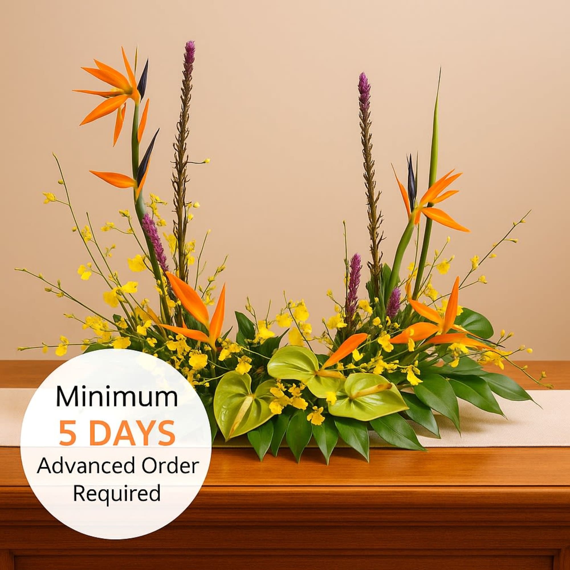 Low tropical arrangement with orange and yellow flowers on a wooden surface