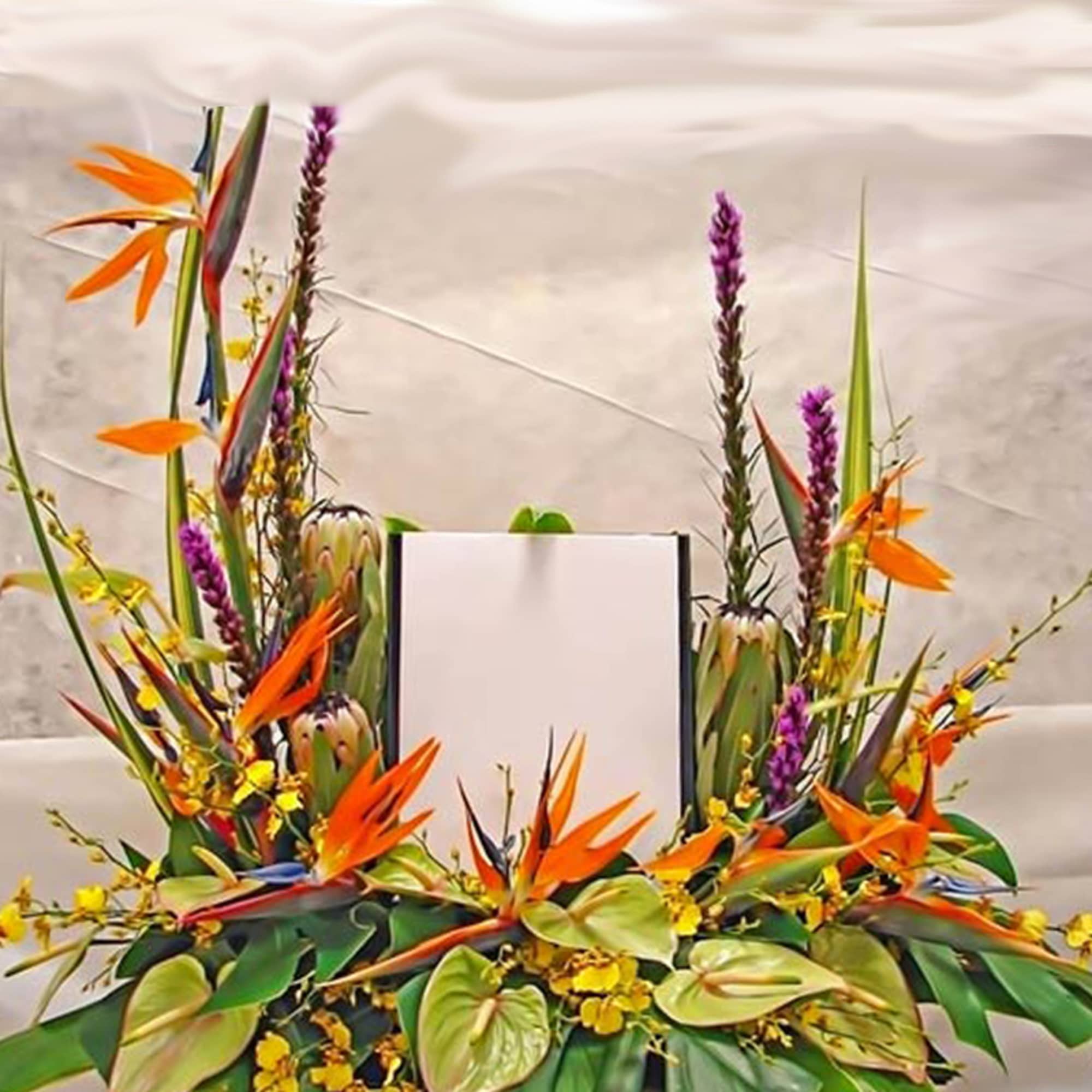 Tropical arrangement with orange birds of paradise and yellow blooms framing an upright white card