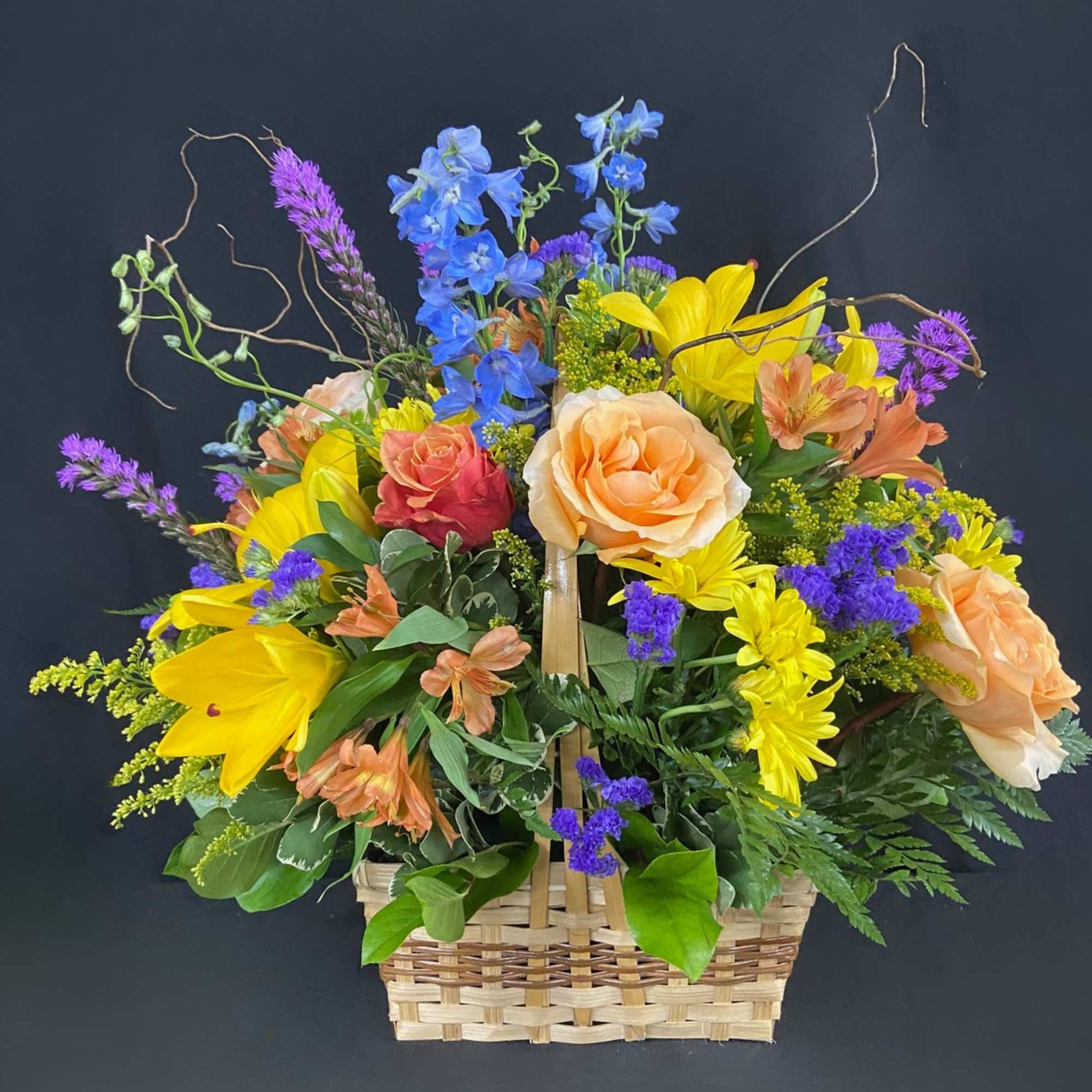 Colorful mixed flower basket with roses, lilies, and blue blooms