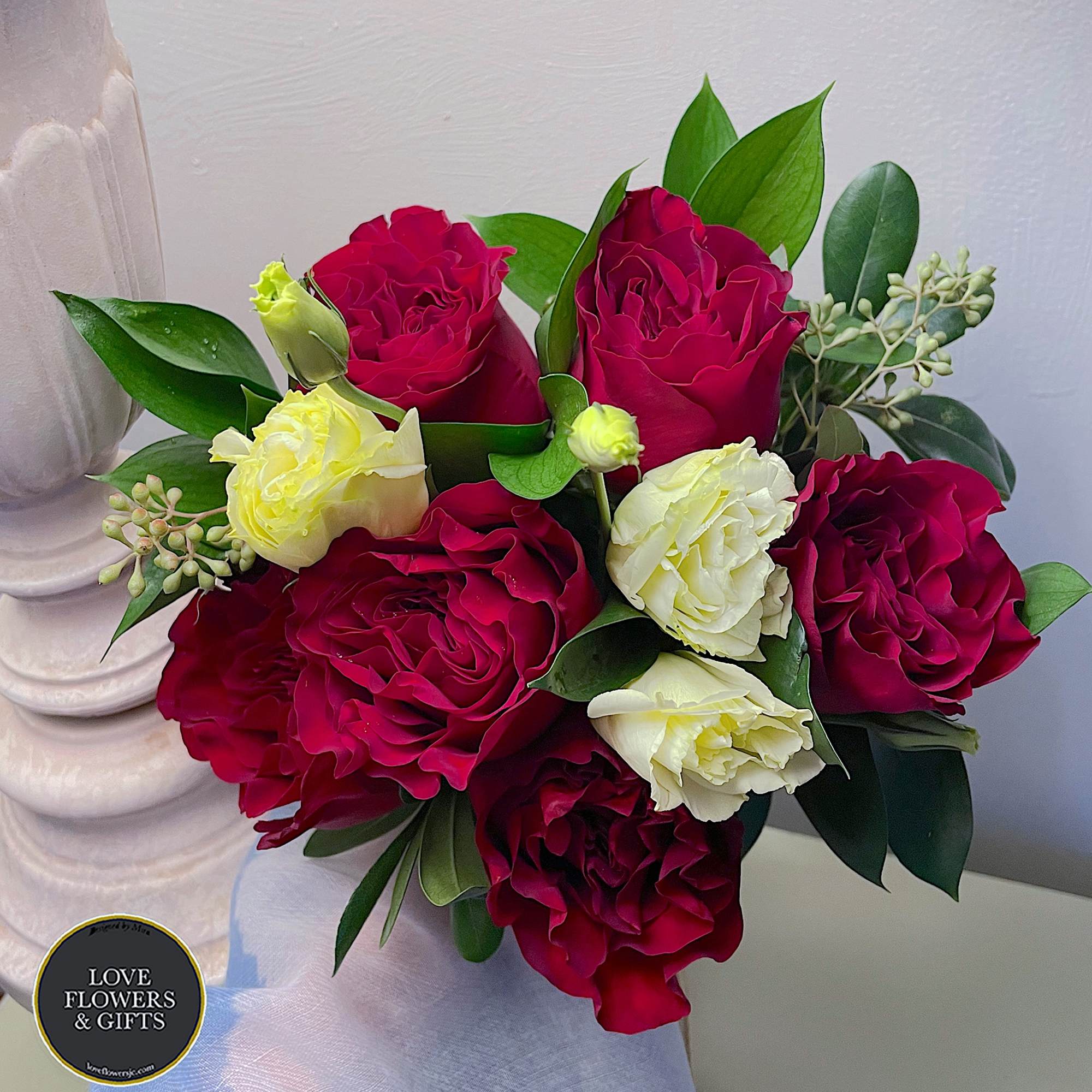 Hand-tied bouquet of deep red roses and pale cream blooms