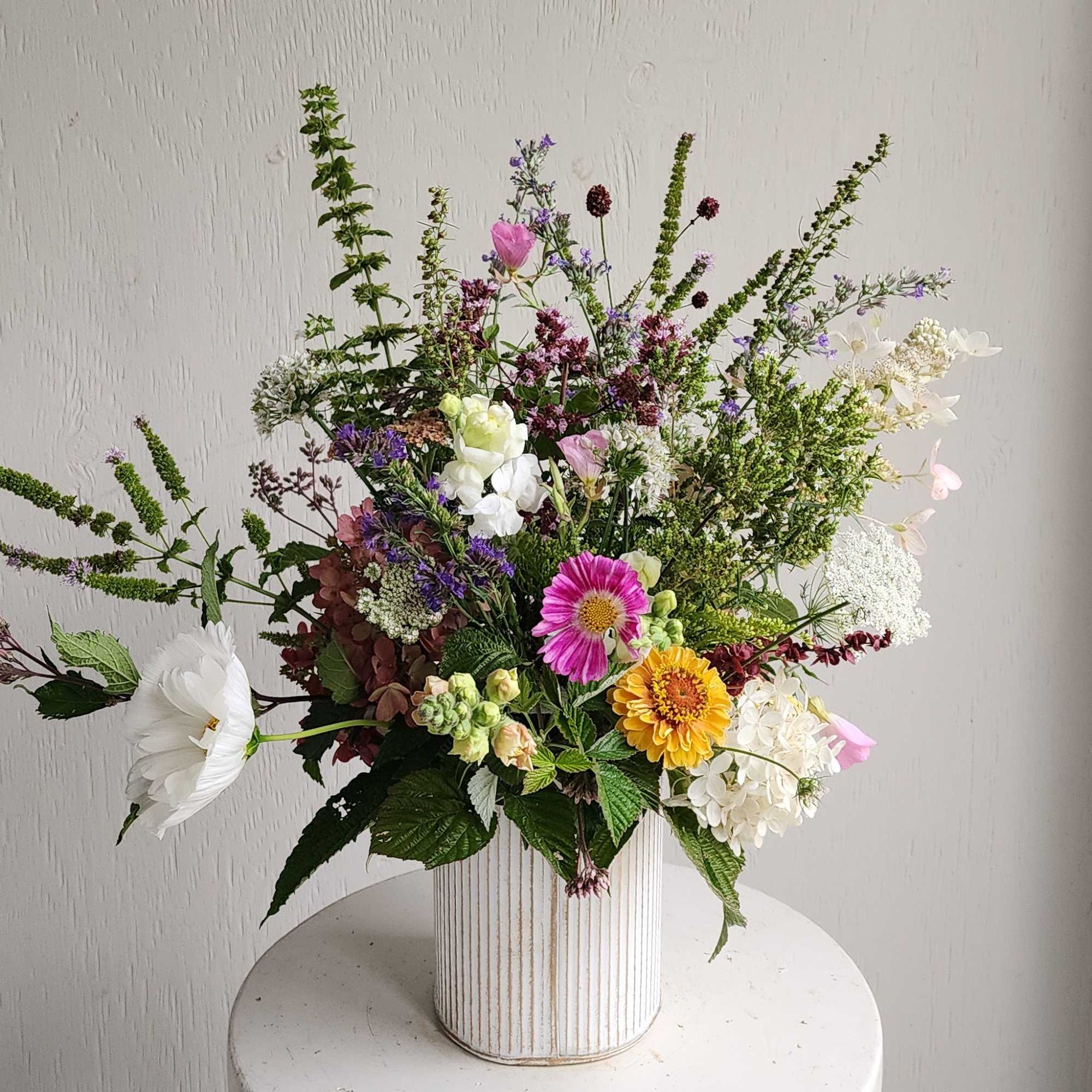 Mixed bouquet in a ribbed white vase with pink, white, yellow, and purple flowers