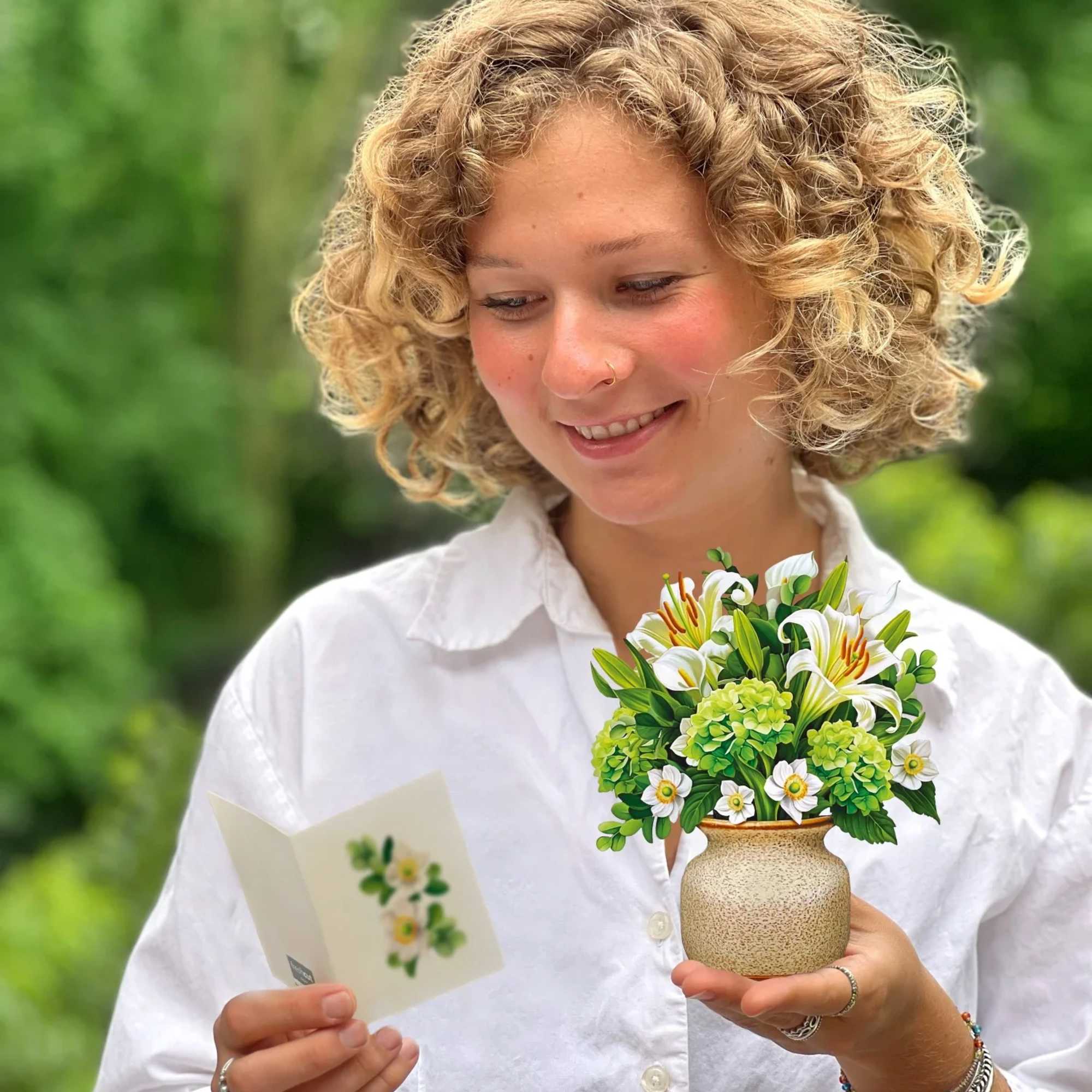 Woman holding a small flower arrangement and a greeting card