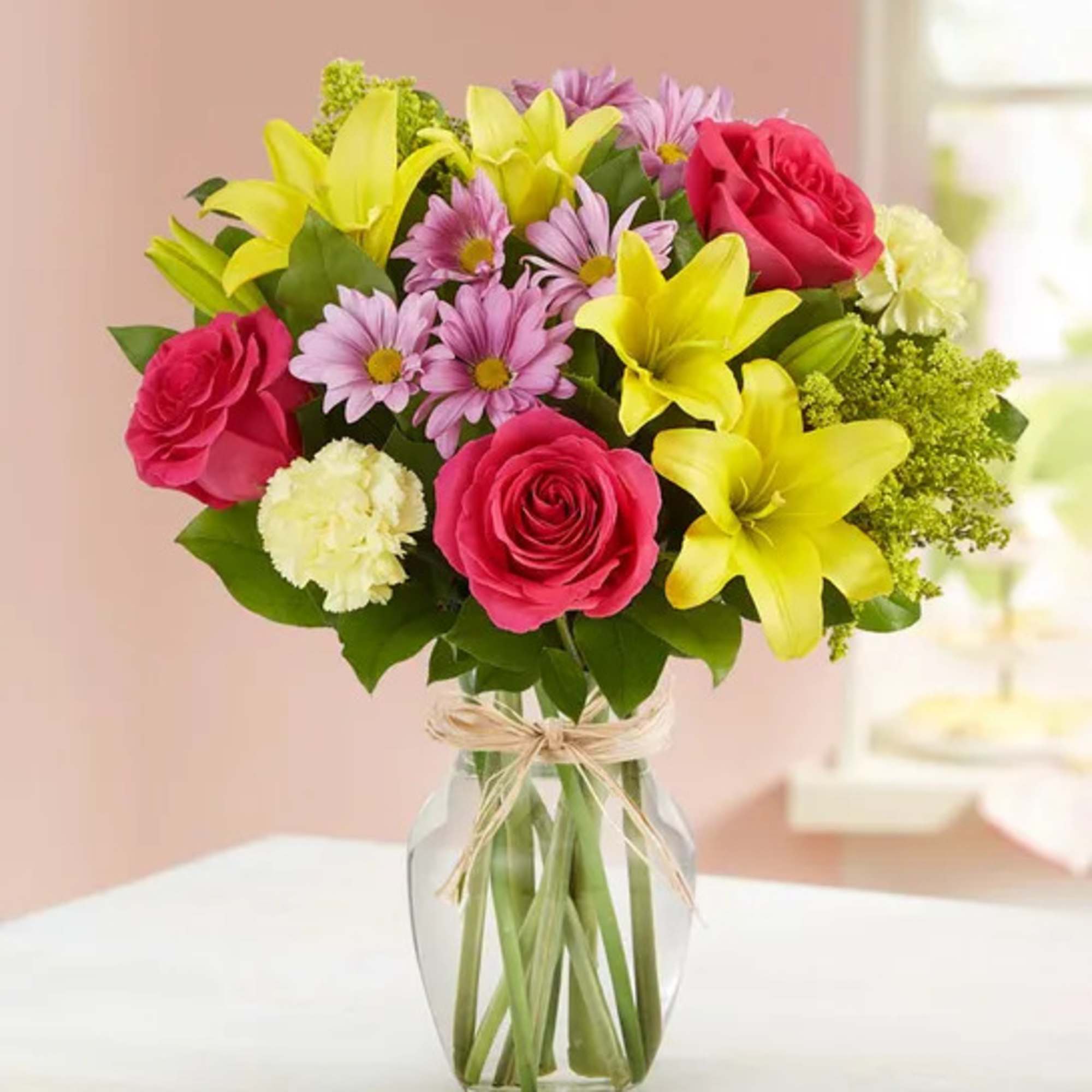 Bouquet of pink roses, yellow lilies, and purple daisies in a glass vase