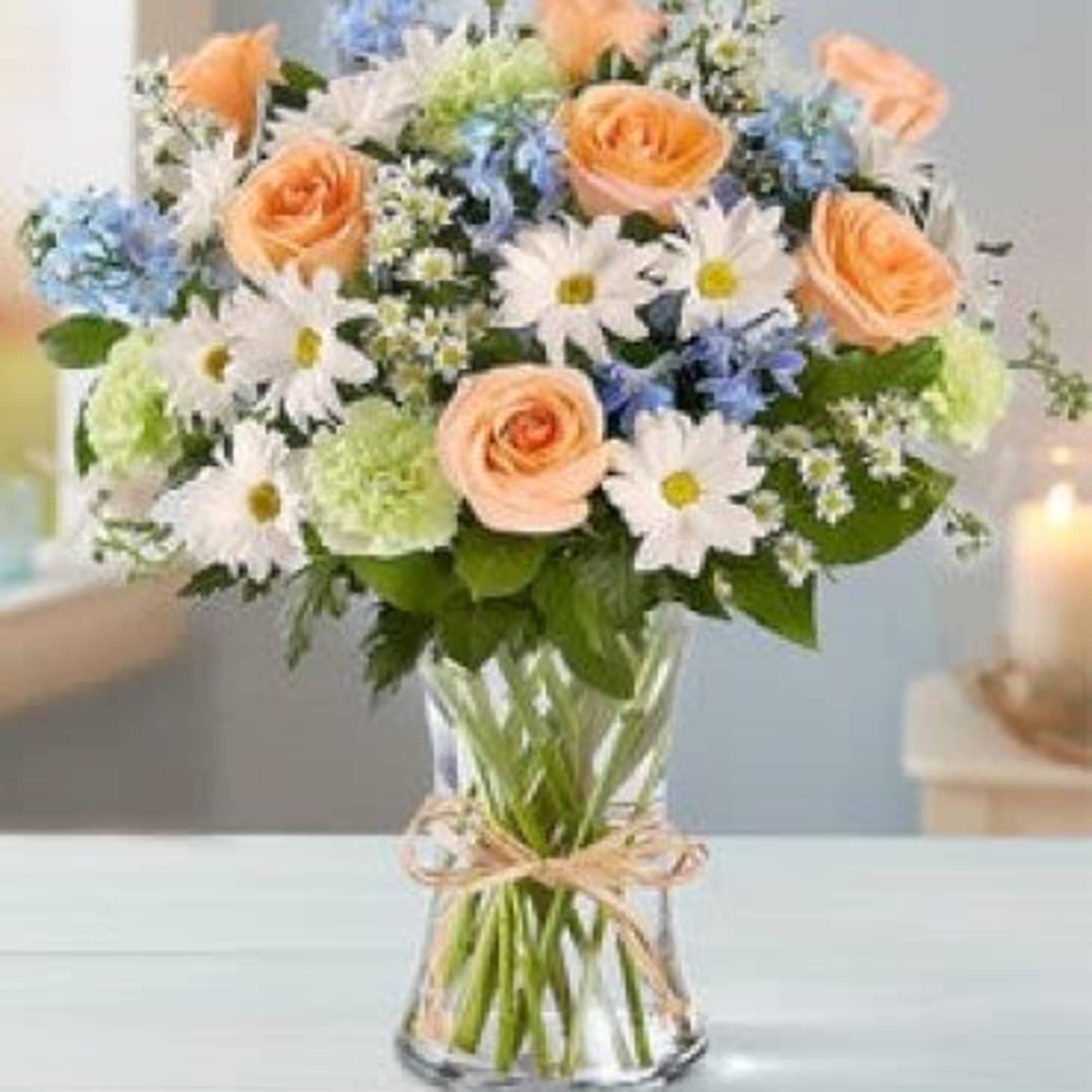 Peach roses and white daisies in a clear glass vase