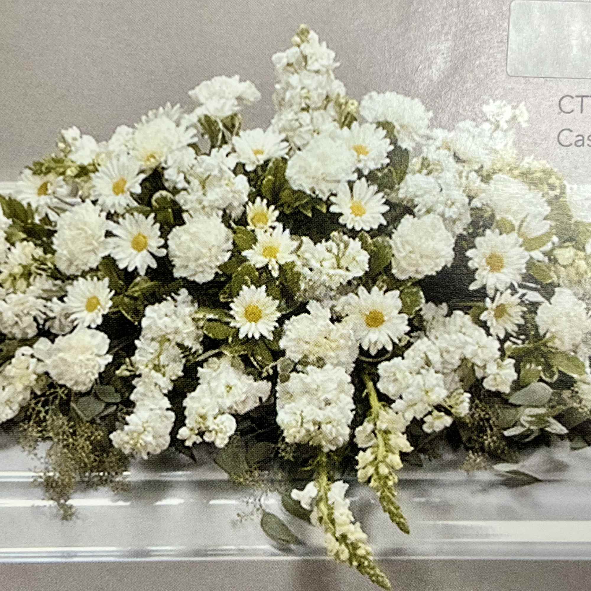 Long white casket spray of daisies and carnations with cascading blooms.