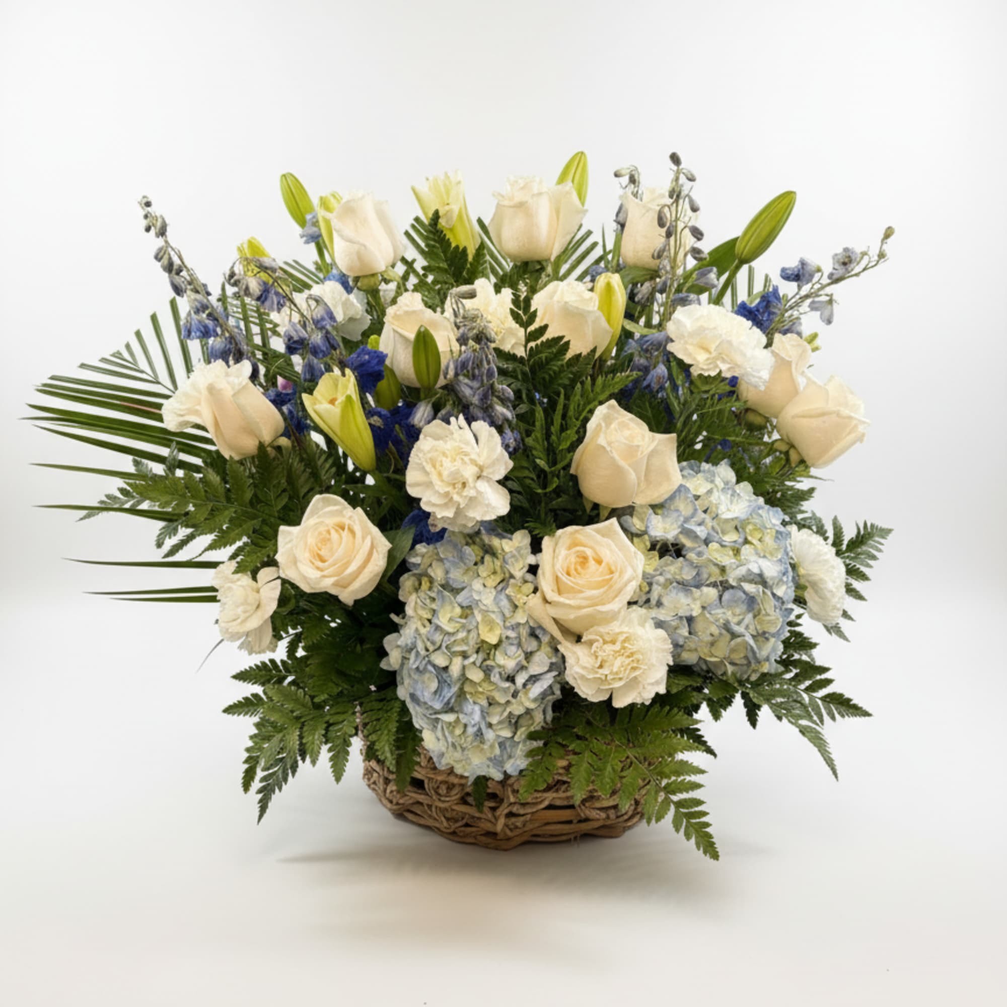 Soft blue hydrangeas and pure white lilies form a calm, reverent focal