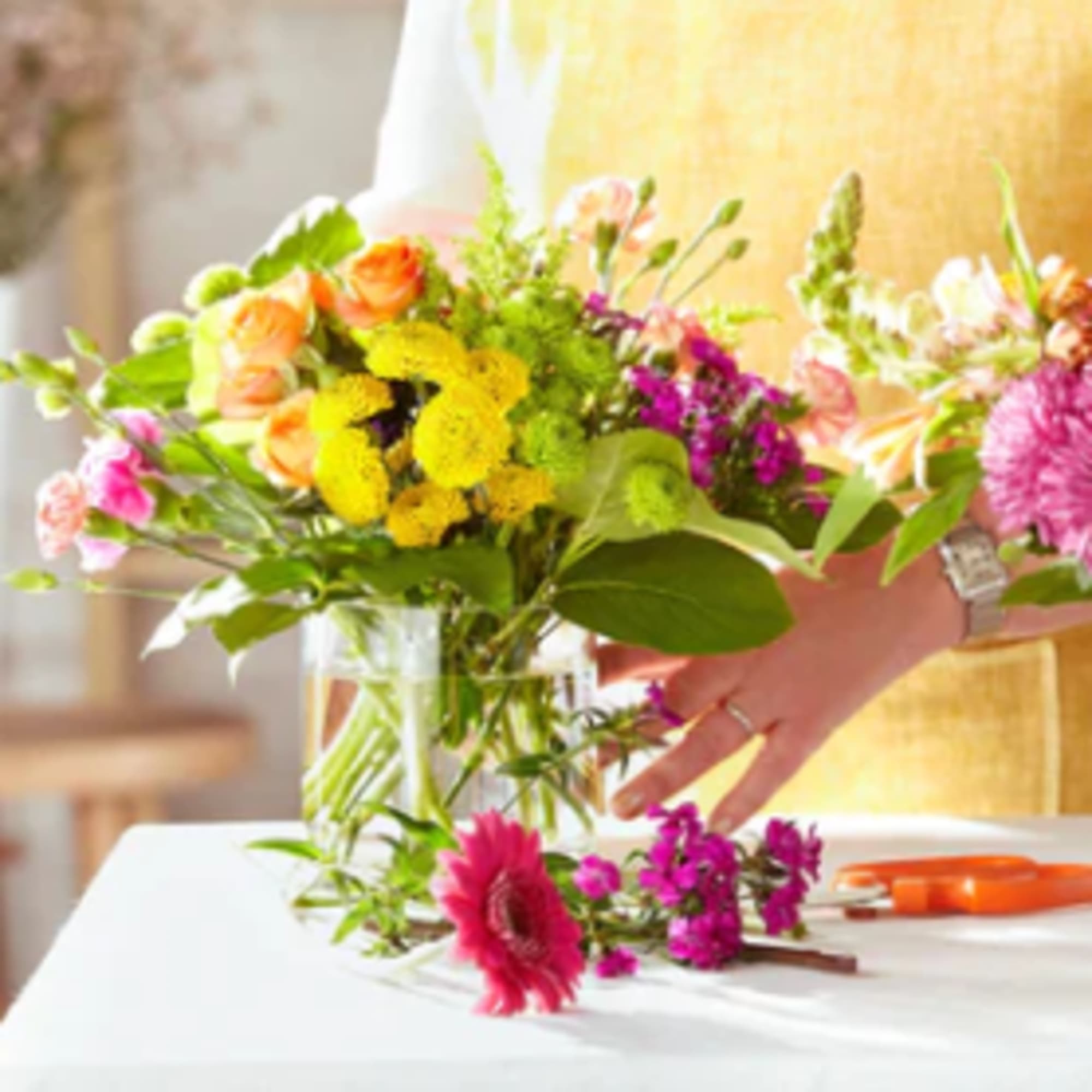 Two colorful flower bouquets in glass vases on a table