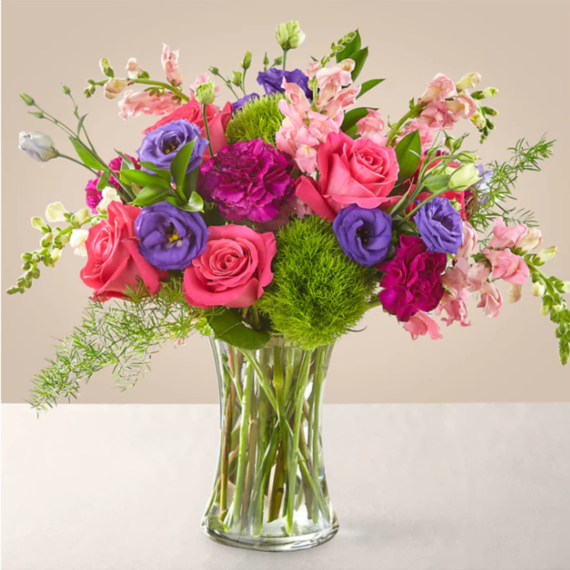 Mixed pink and purple flowers arranged in a clear glass vase