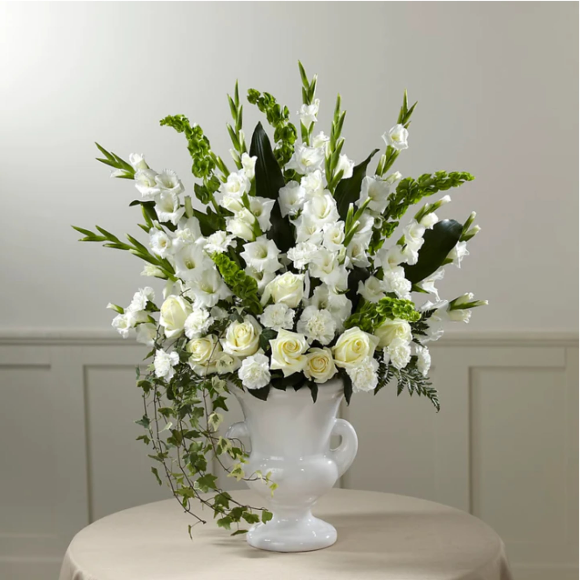 White floral arrangement in a white urn vase