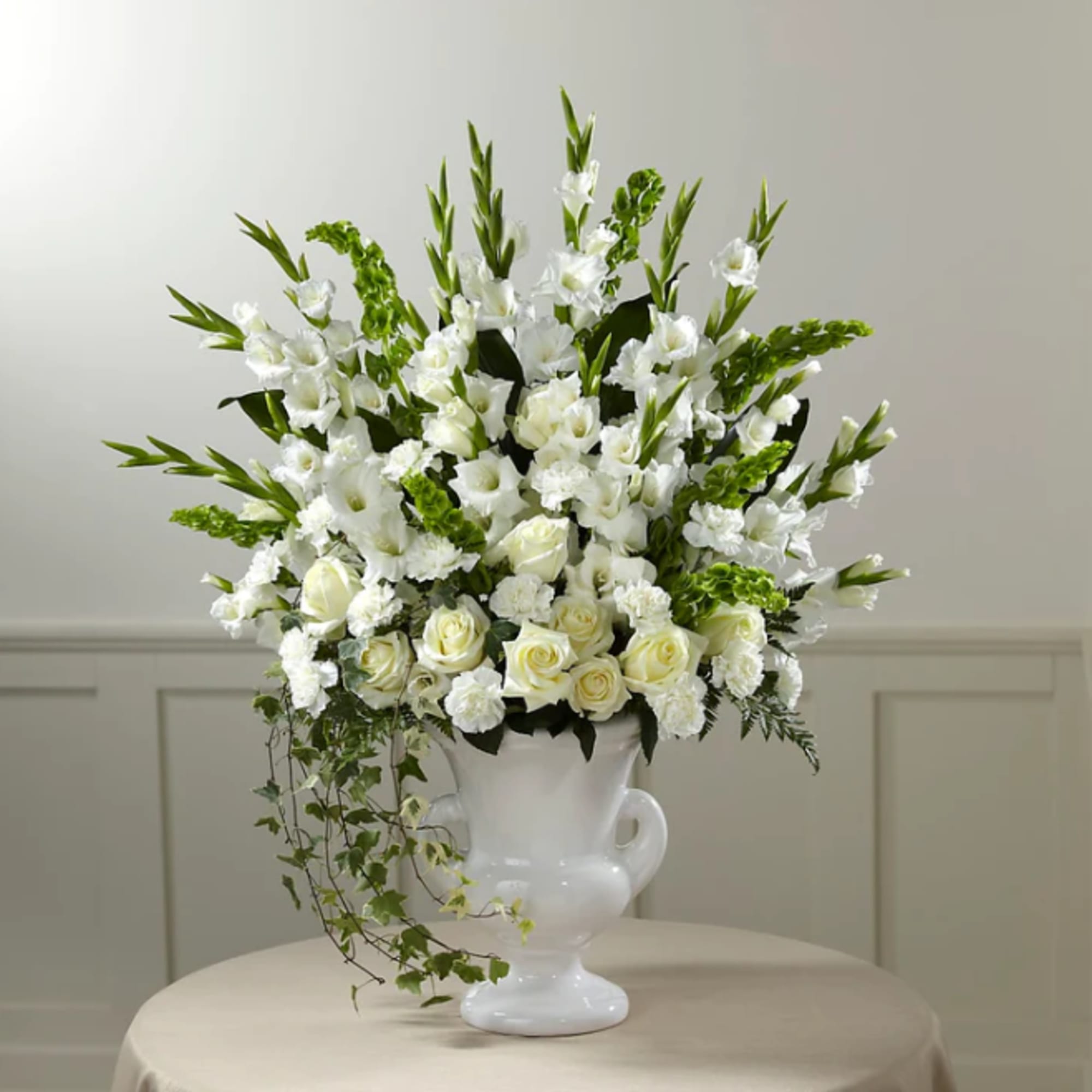White floral arrangement in a white urn vase