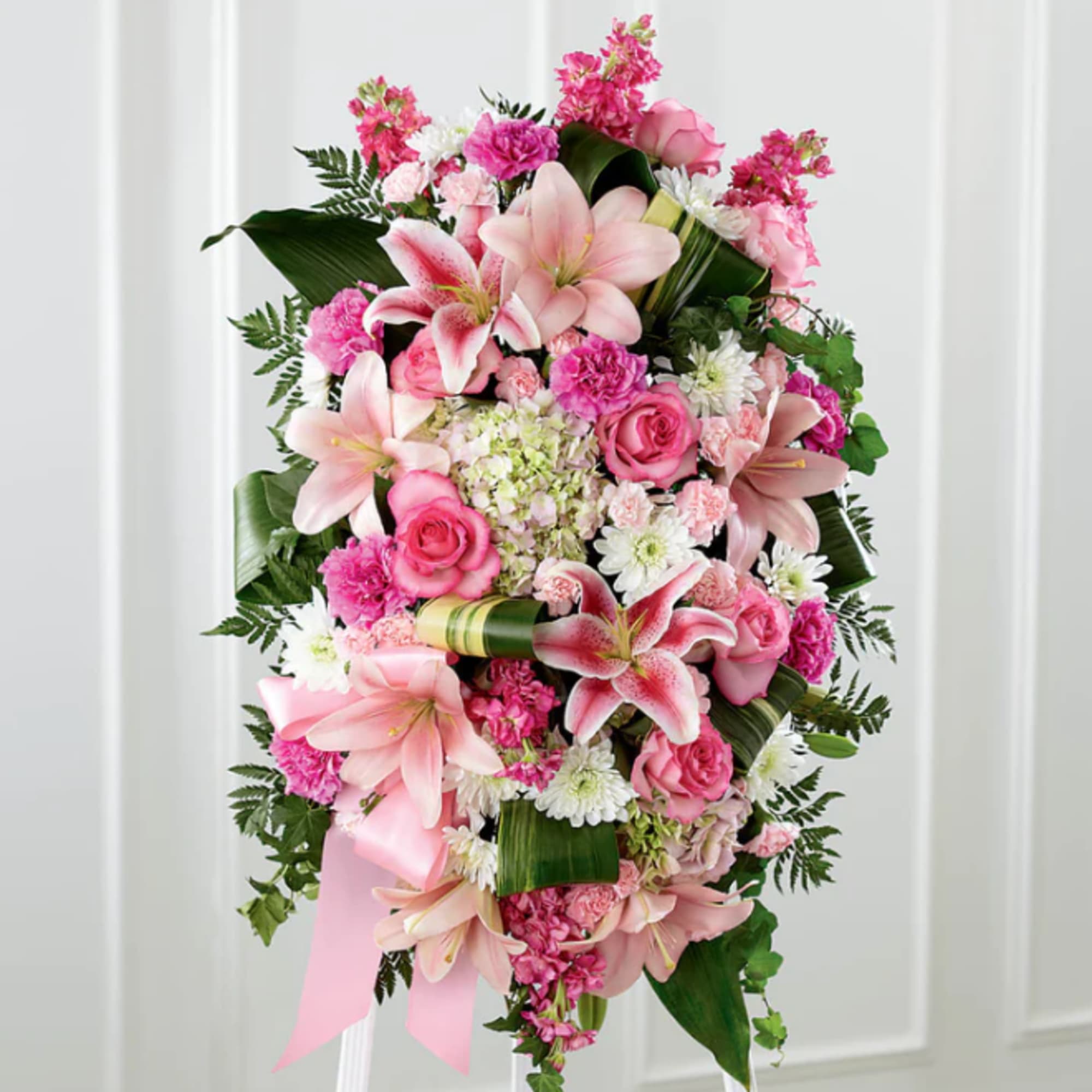 Pink and white floral standing spray with lilies, roses, and carnations
