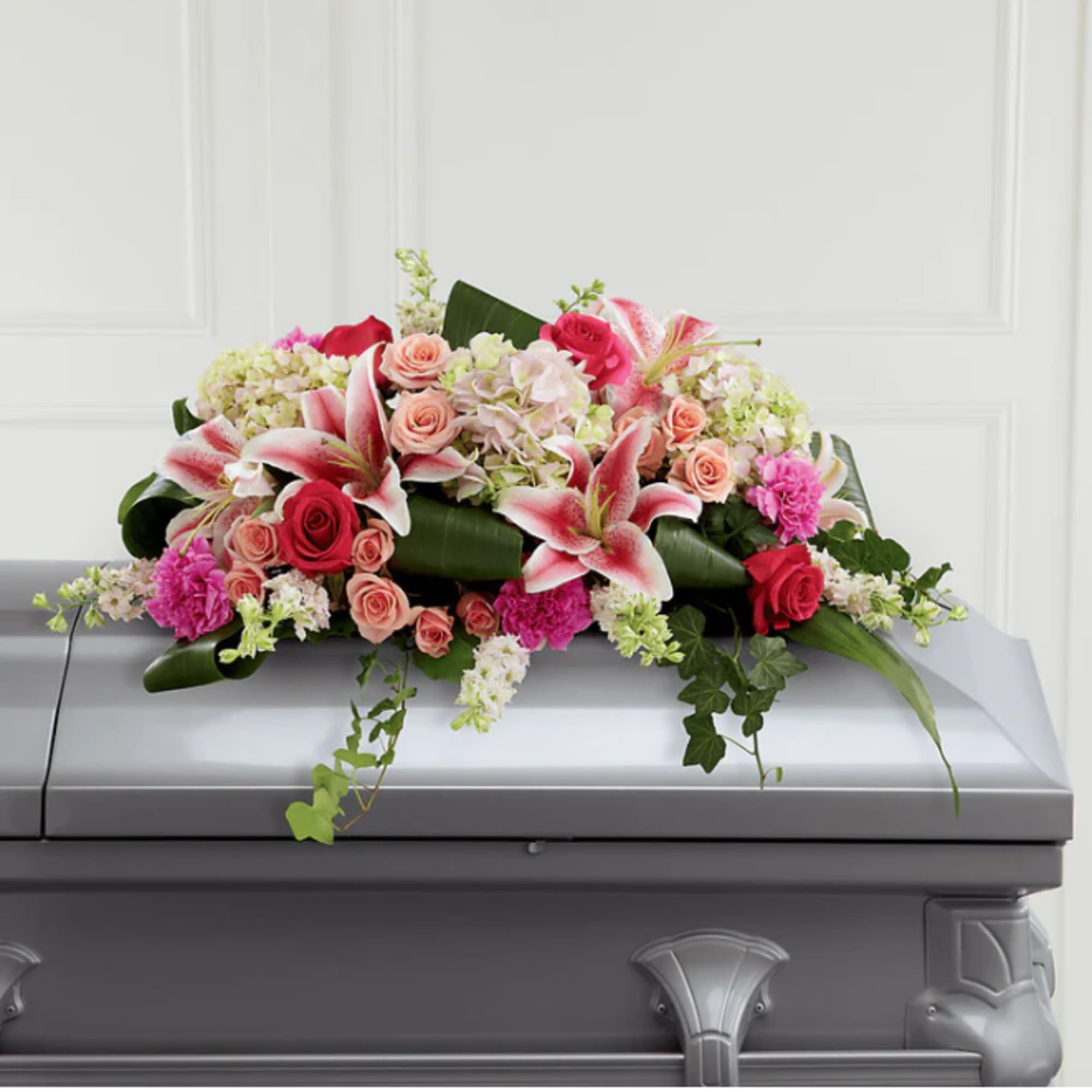 Floral casket spray with pink lilies, roses, and hydrangeas