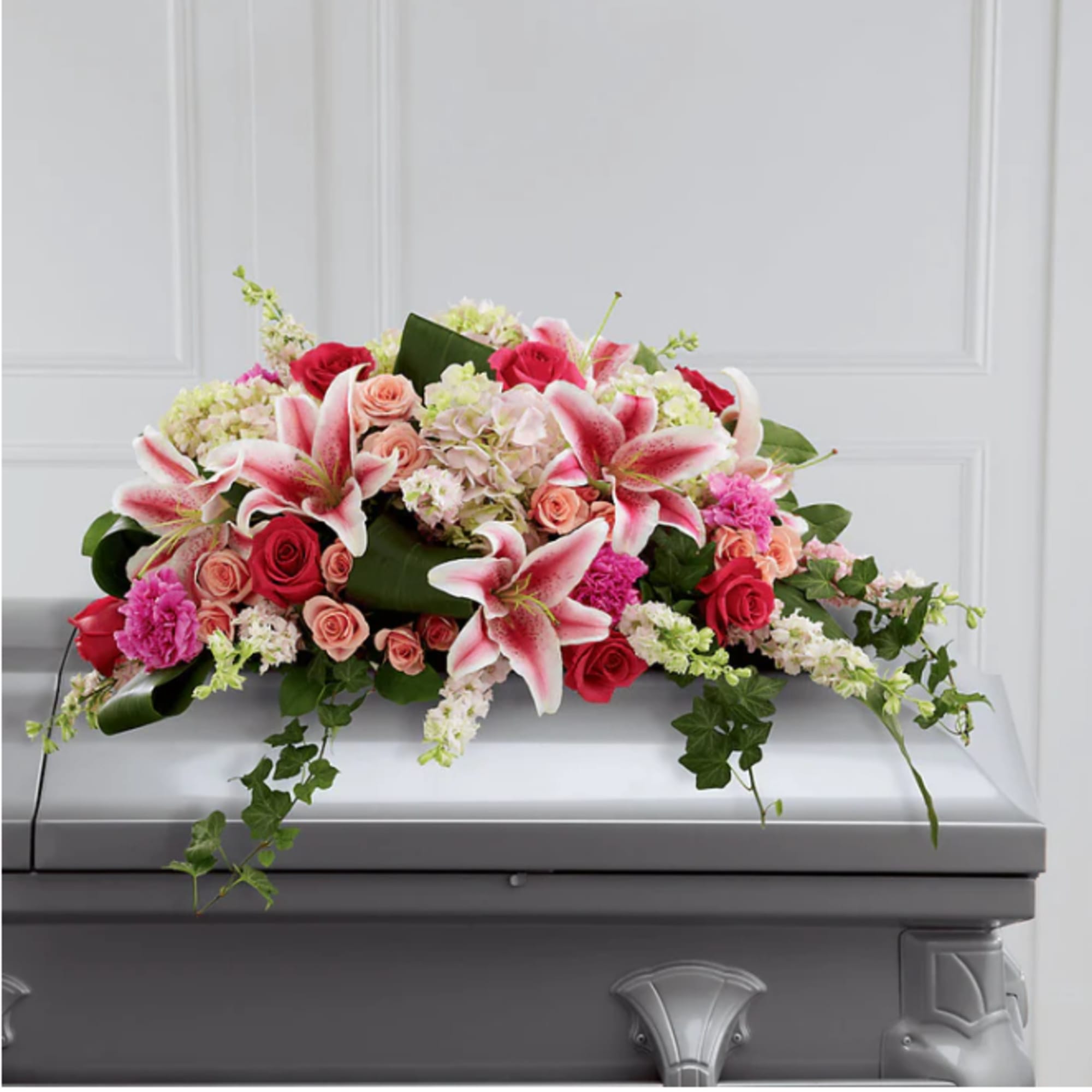 Pink and white floral casket spray with lilies and roses