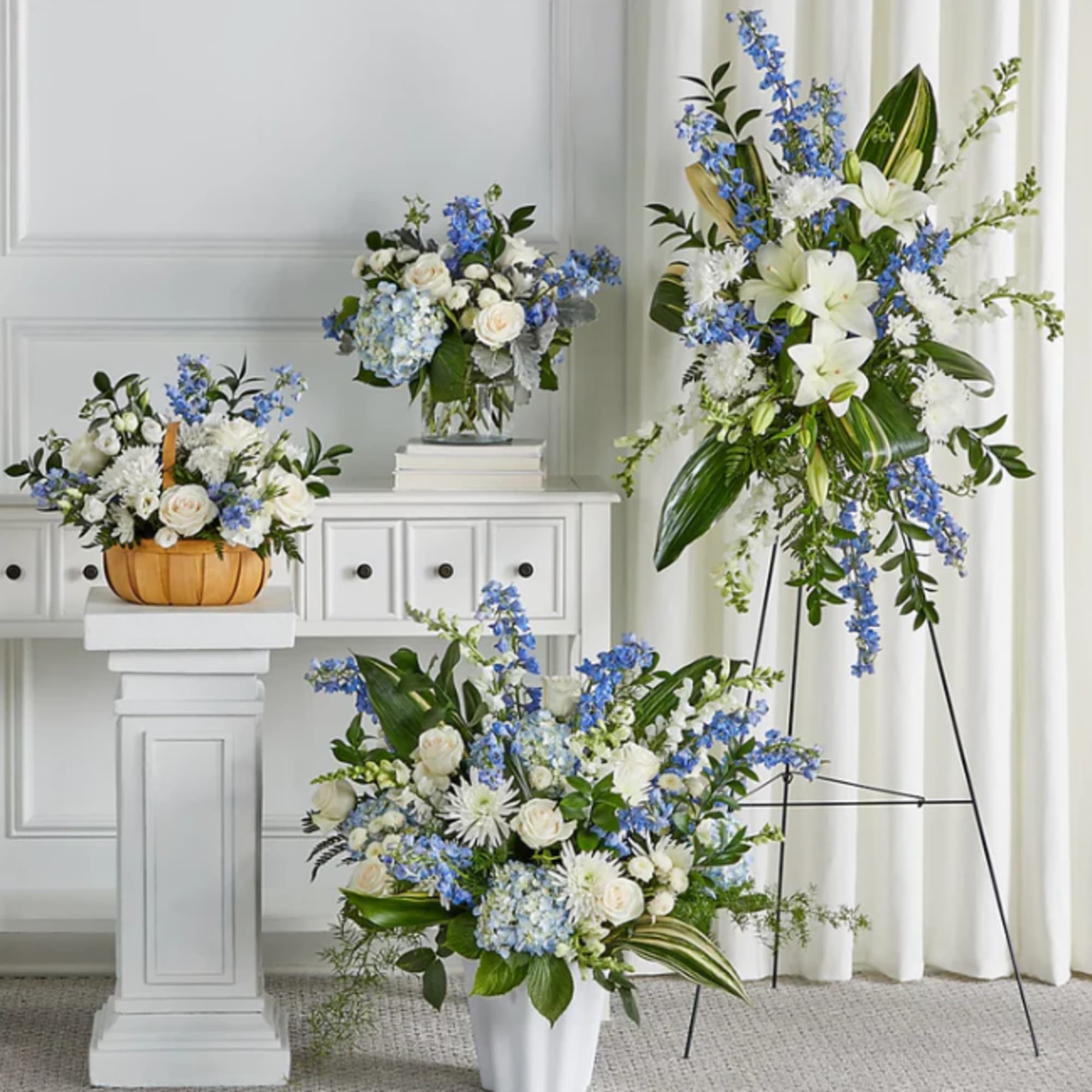 Three blue and white floral arrangements in vases and a basket