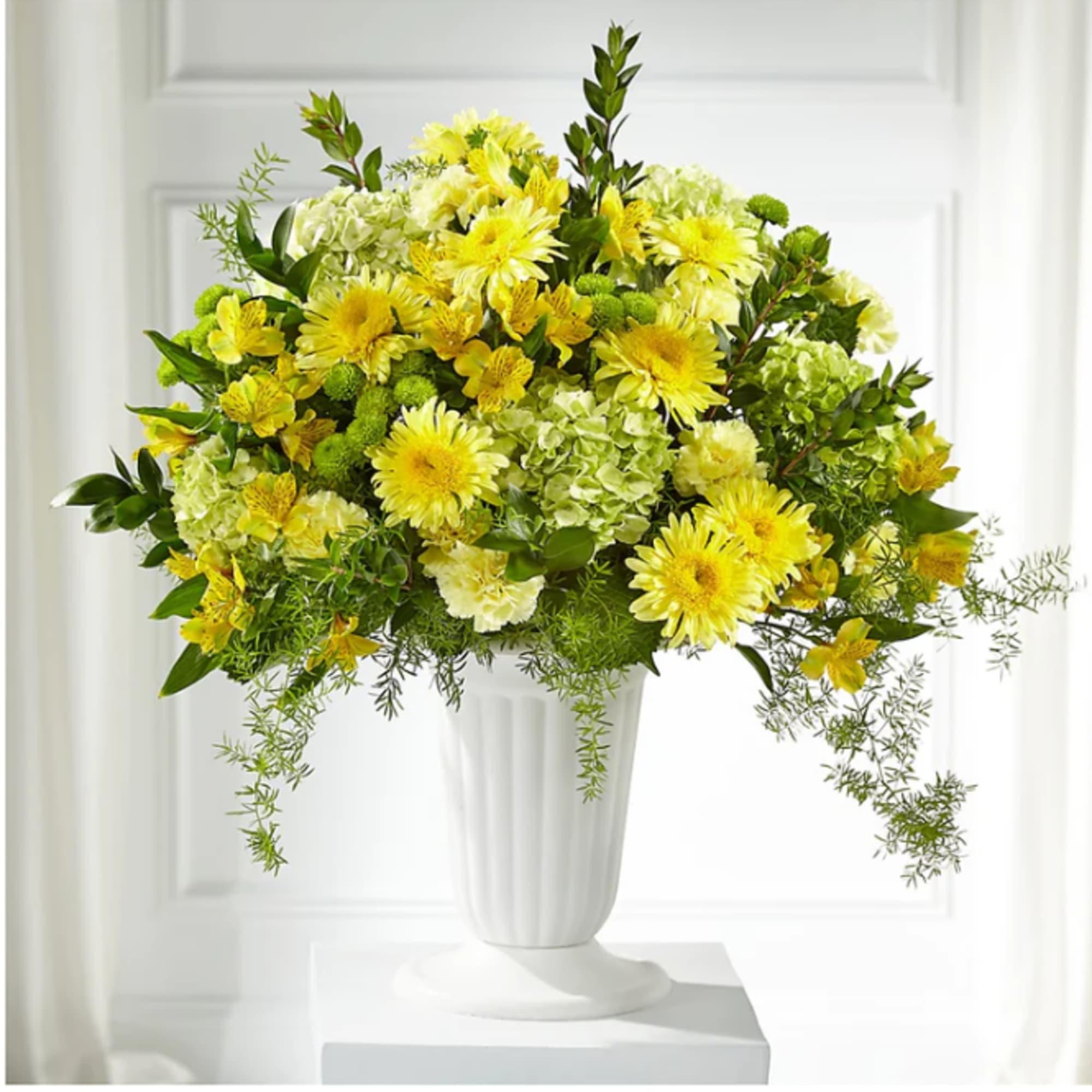 Yellow and green floral arrangement in a white vase