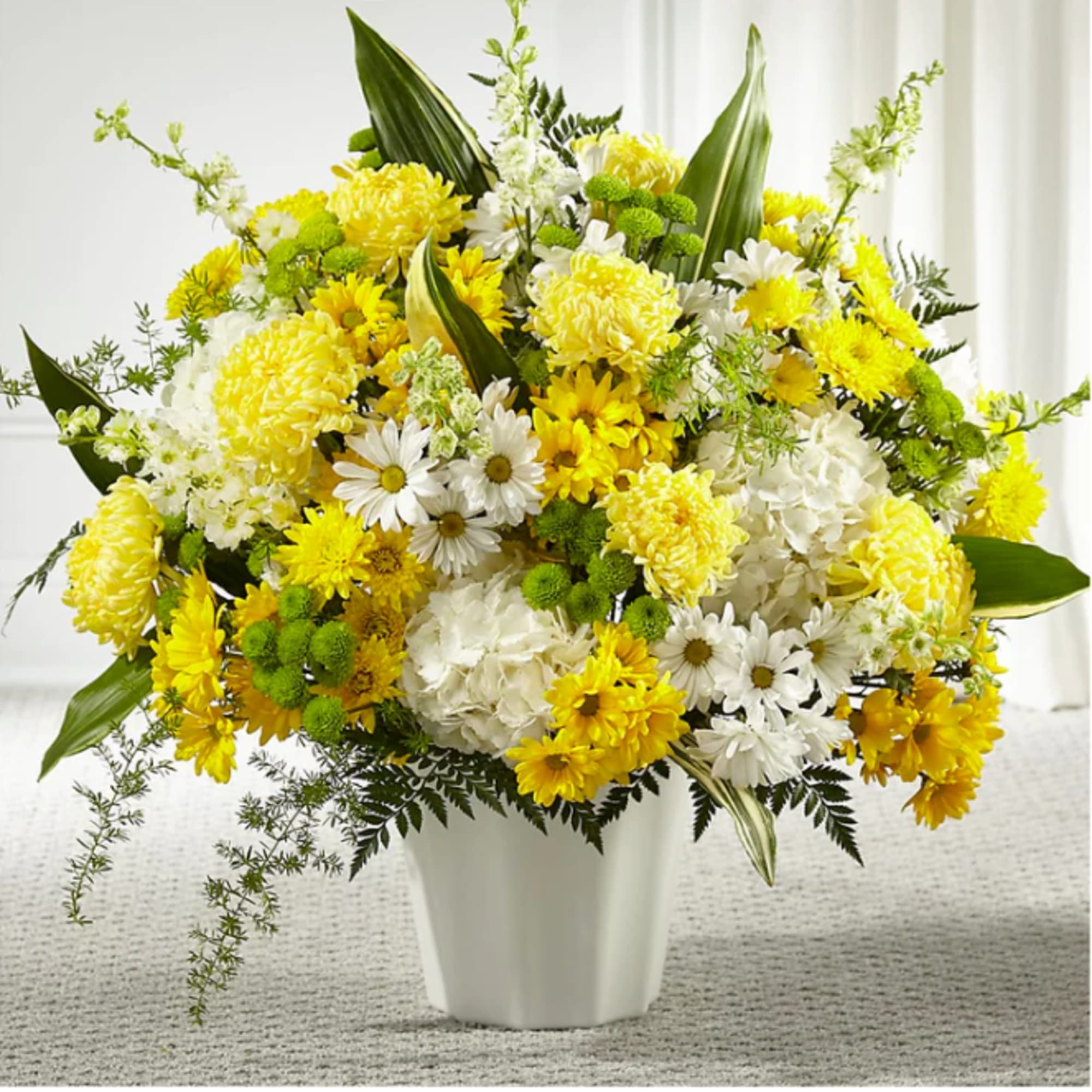 Yellow and white mixed flower arrangement in a white vase