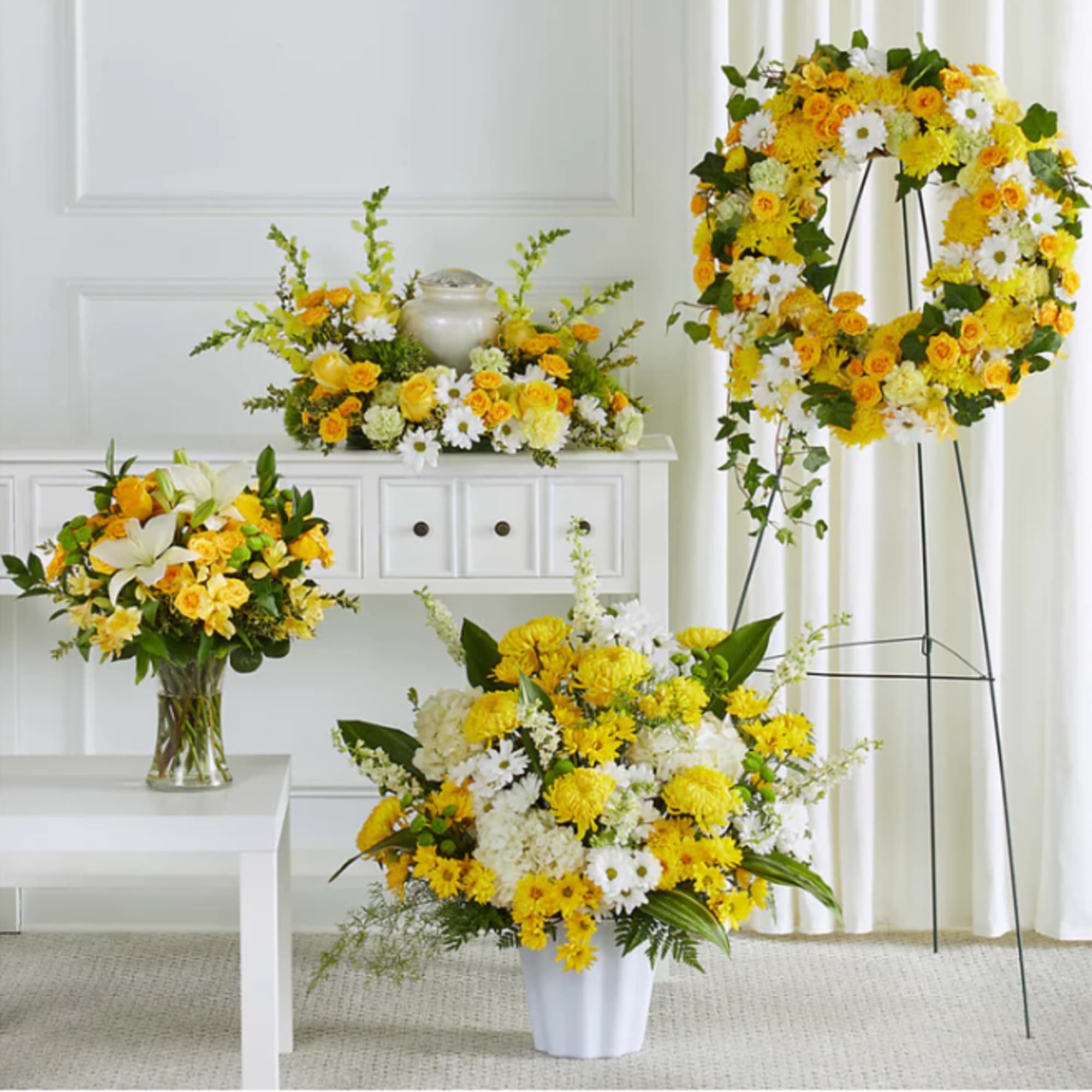 Yellow and white floral arrangements with a wreath on a stand