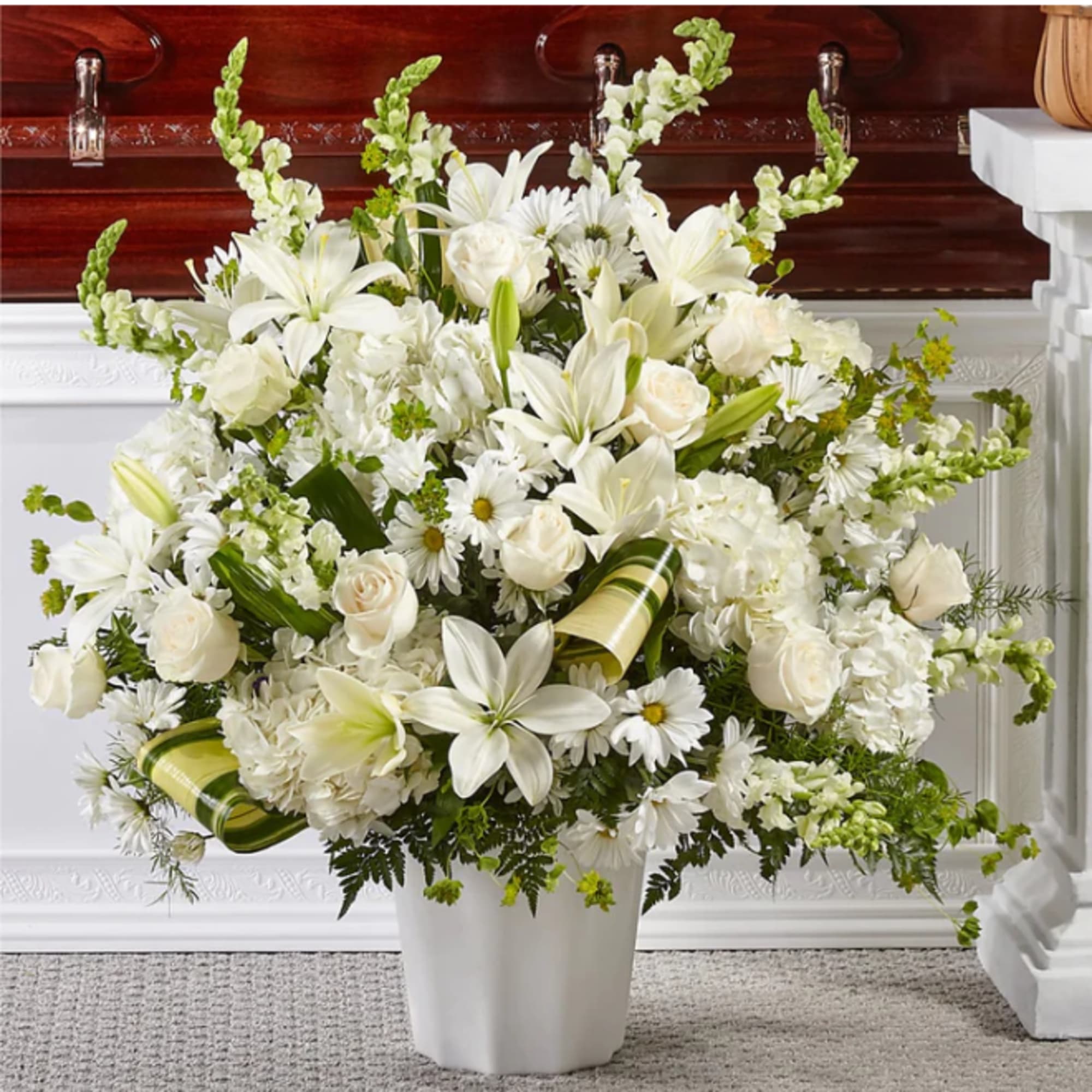 Large white floral arrangement in a white vase with lilies and roses