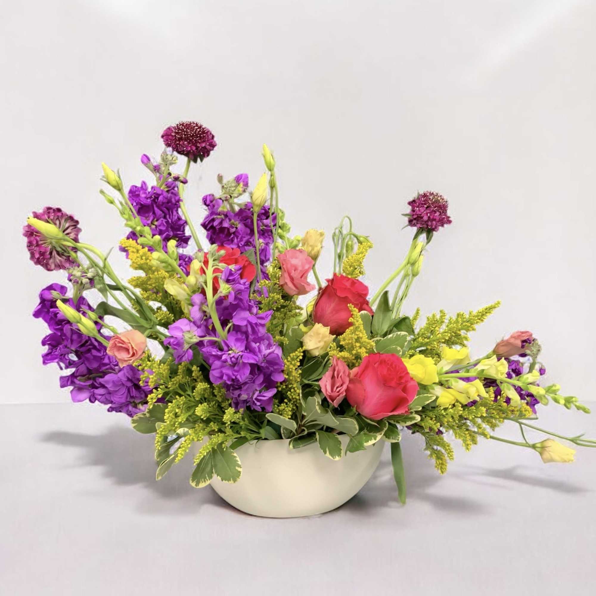 Colorful mixed flower arrangement in a white bowl vase