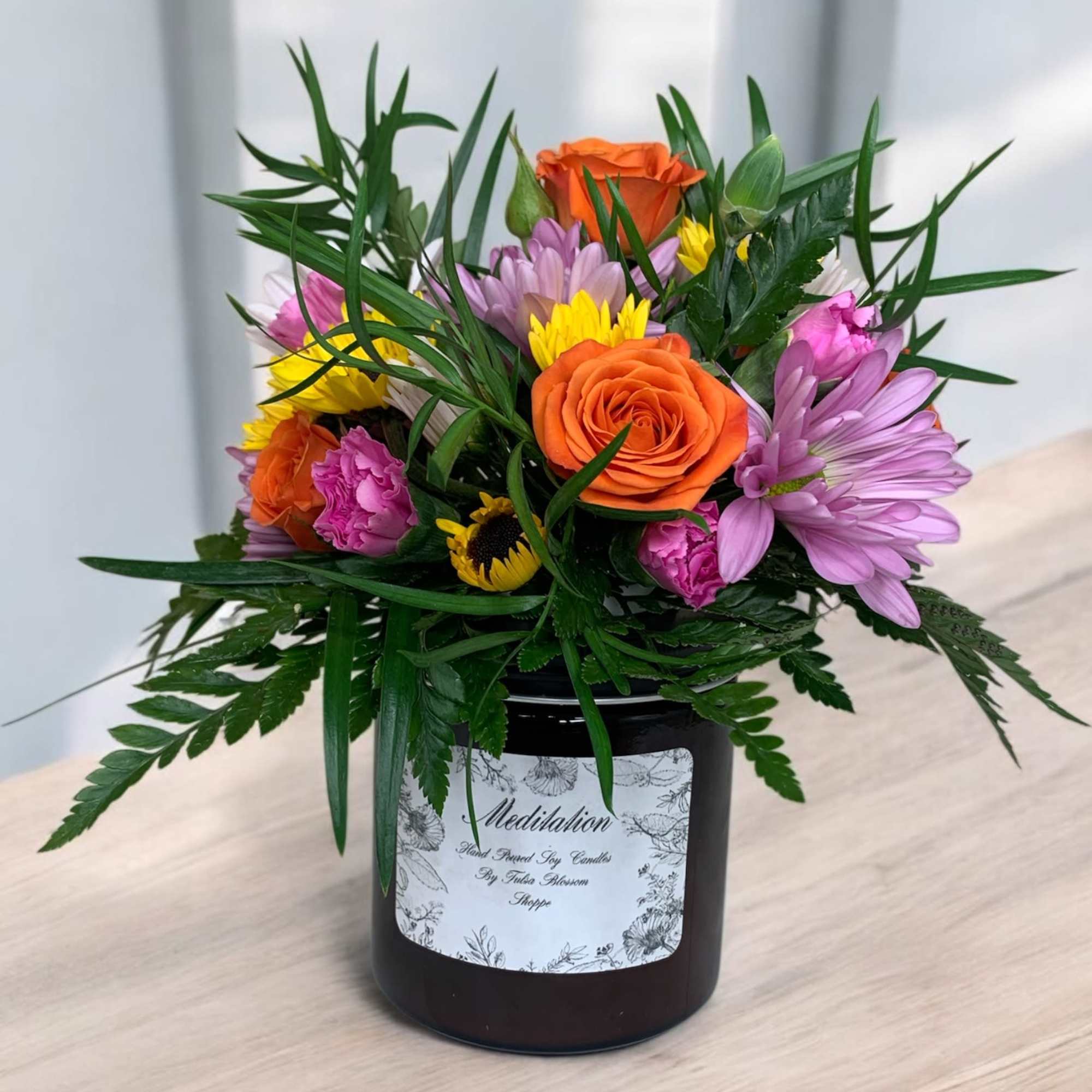 Mixed bouquet in a black jar vase with orange and purple flowers