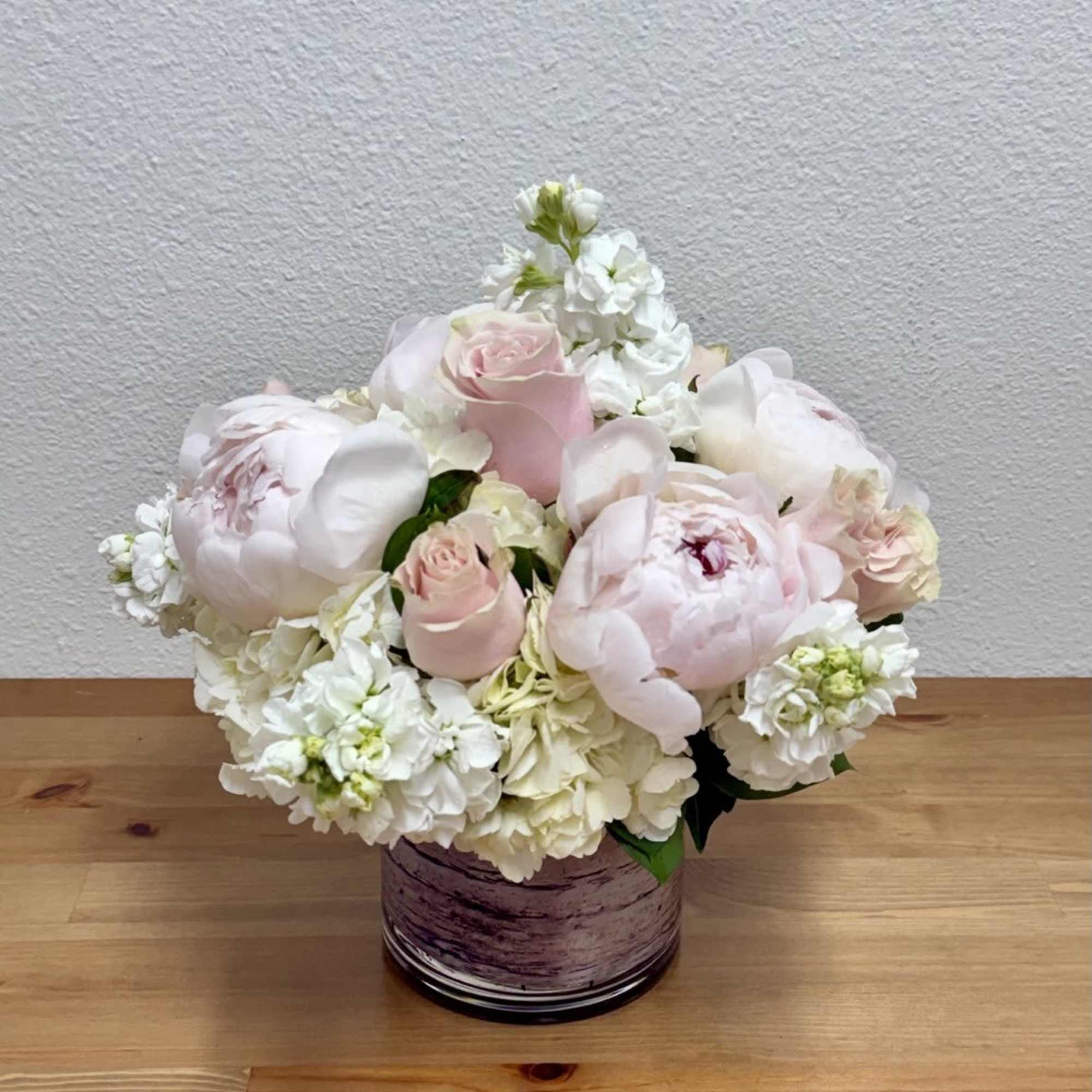 Blush pink roses and white peonies in a purple glass vase