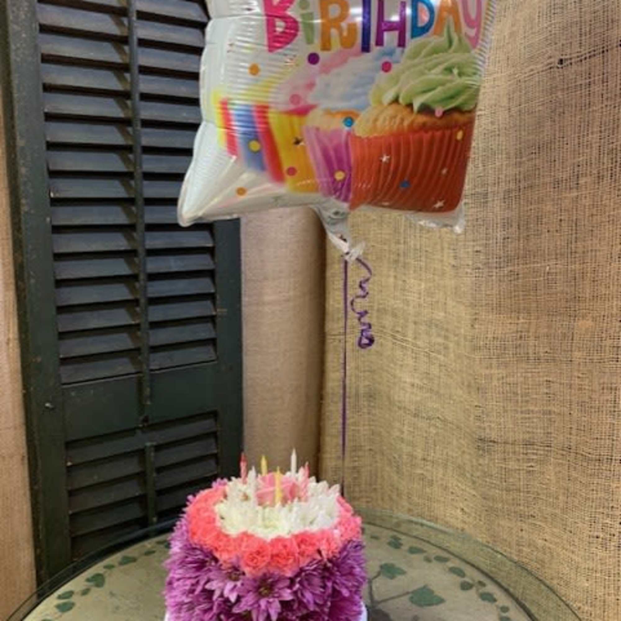 Birthday balloon above a round pink and white flower arrangement