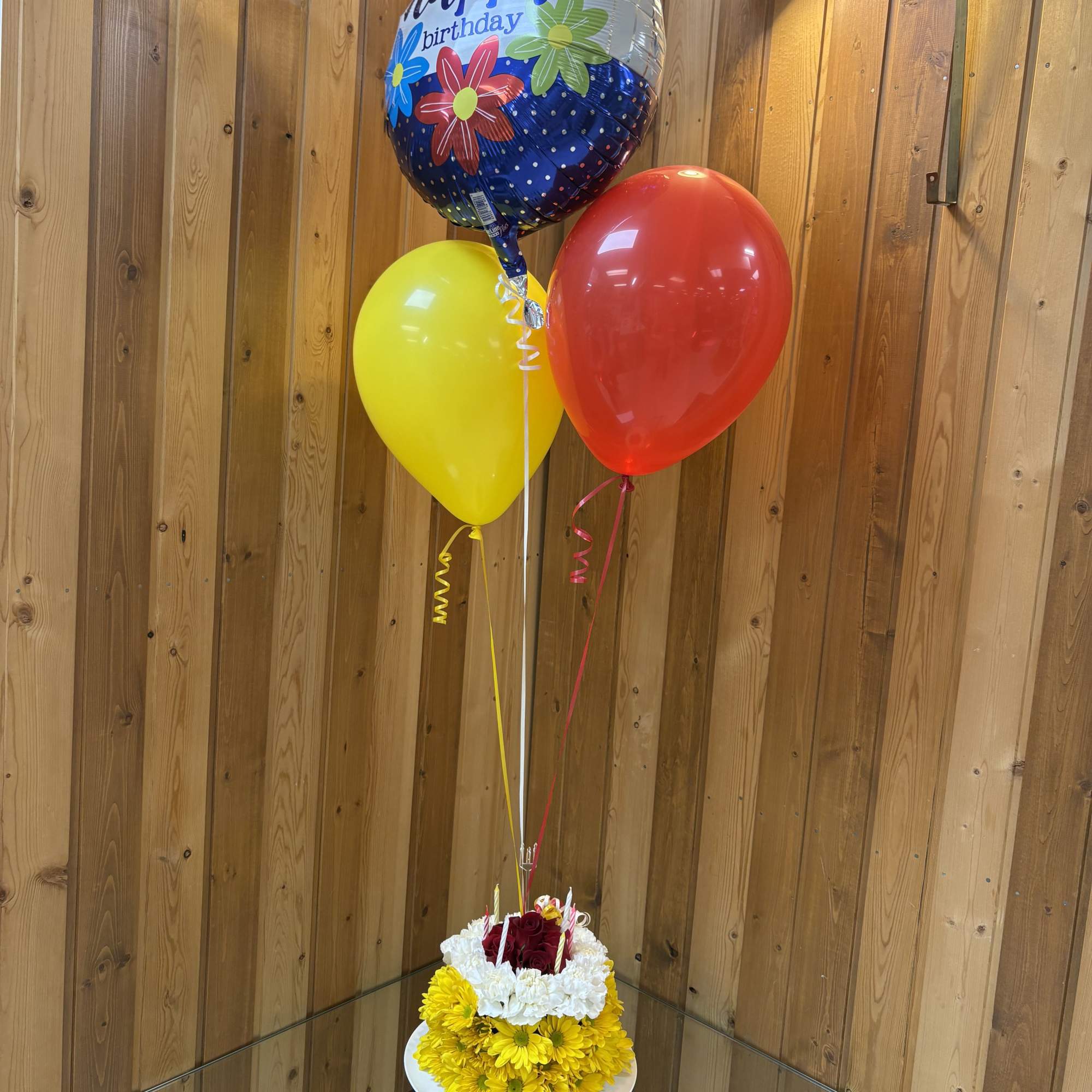 Birthday balloon bouquet with a floral base in a white container