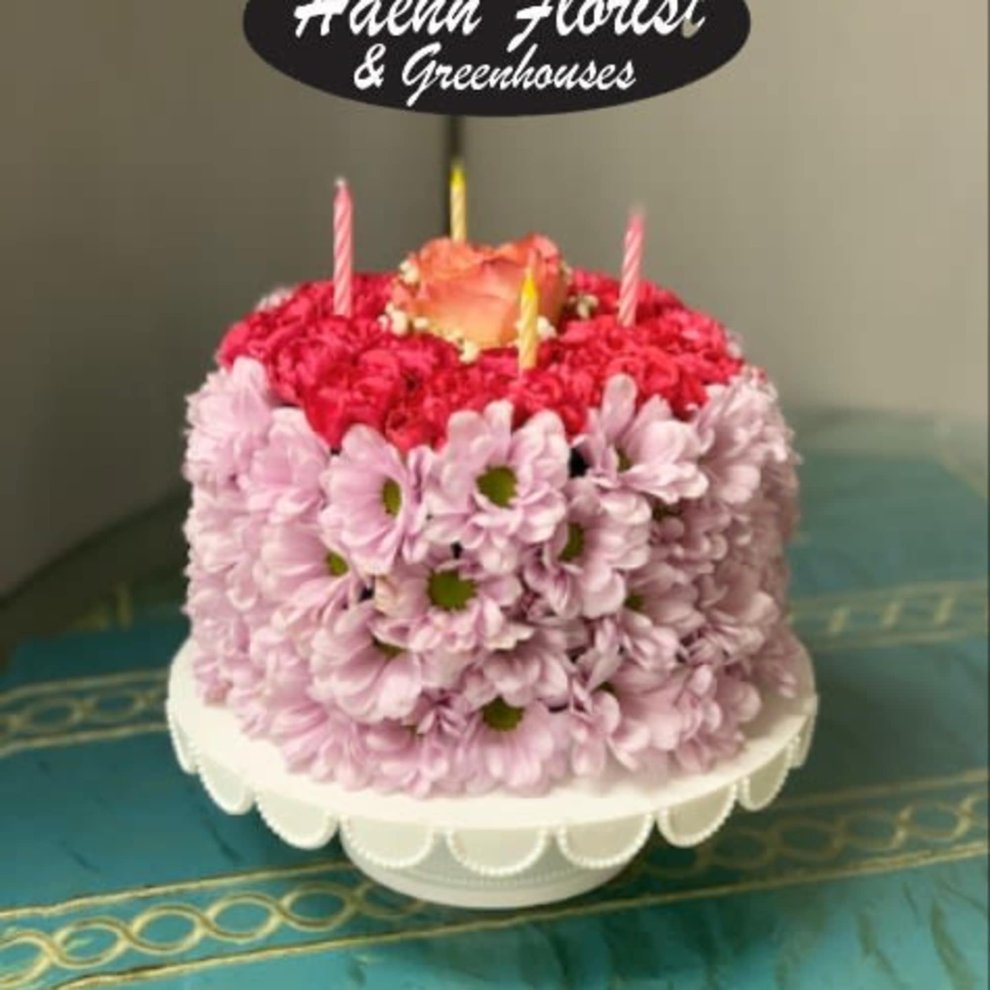 Flower-covered birthday cake with candles and a topper