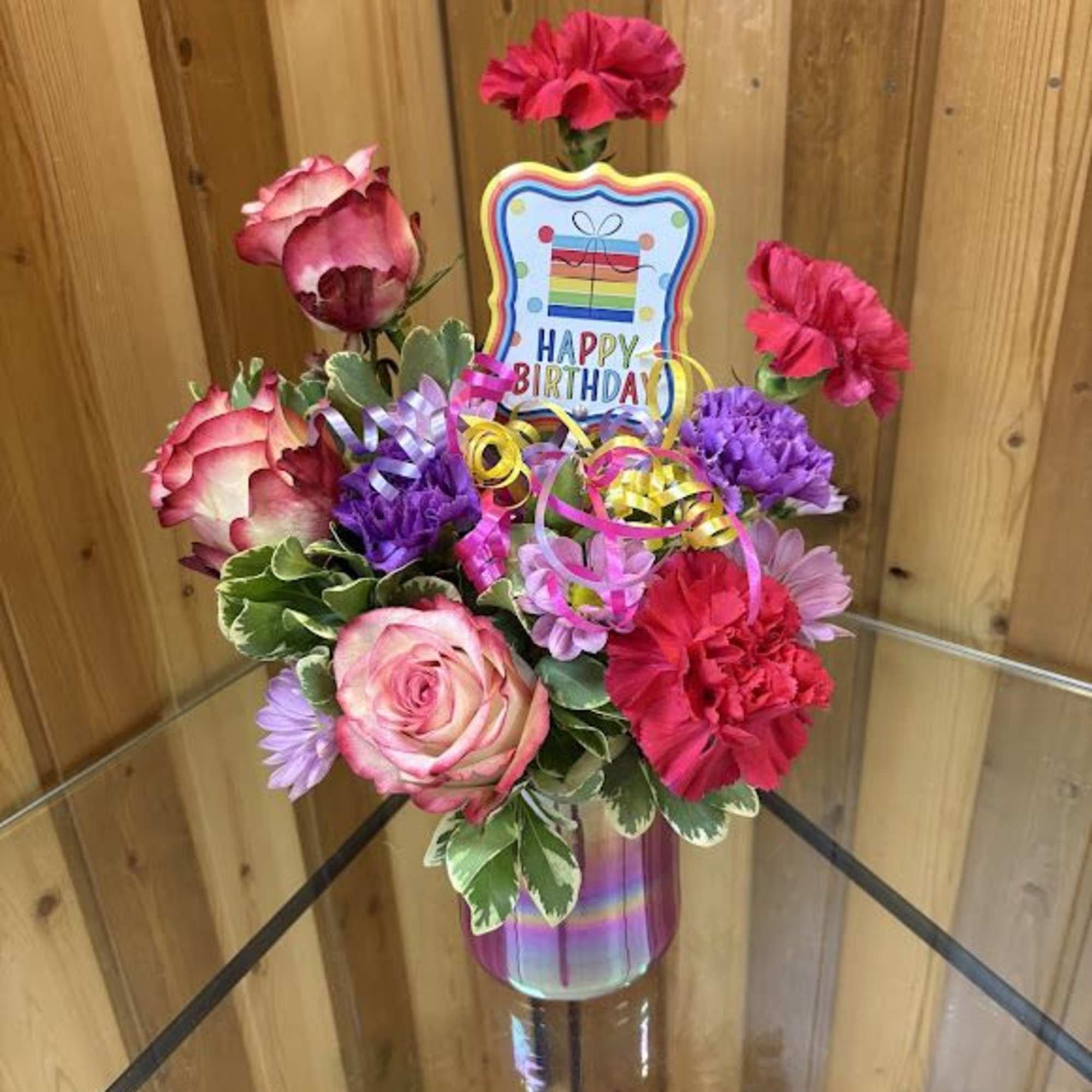 Pink and purple flower arrangement in a vase with a Happy Birthday sign