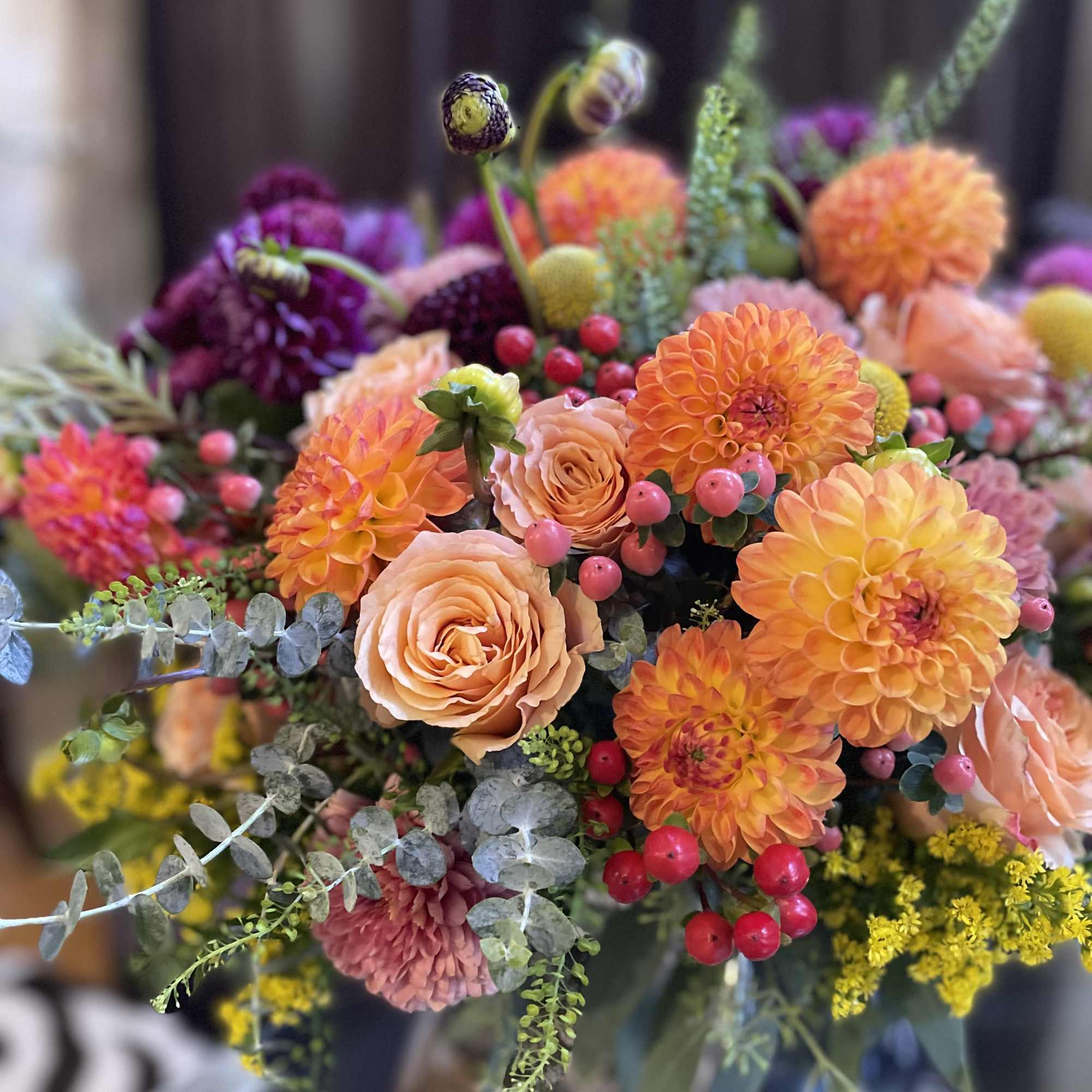 Bouquet of orange dahlias and peach roses with berry accents