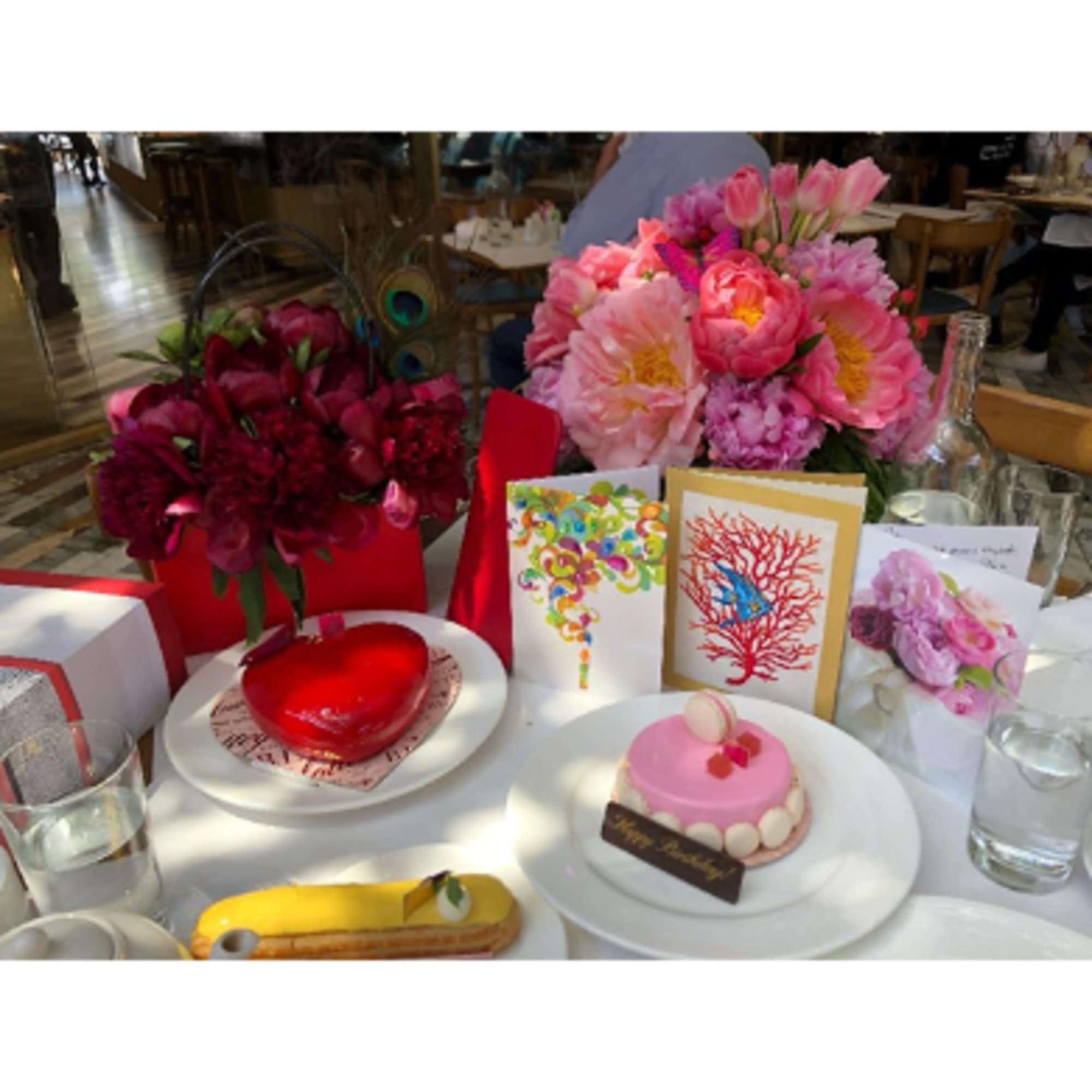 Pink floral arrangements on a table with cakes and greeting cards