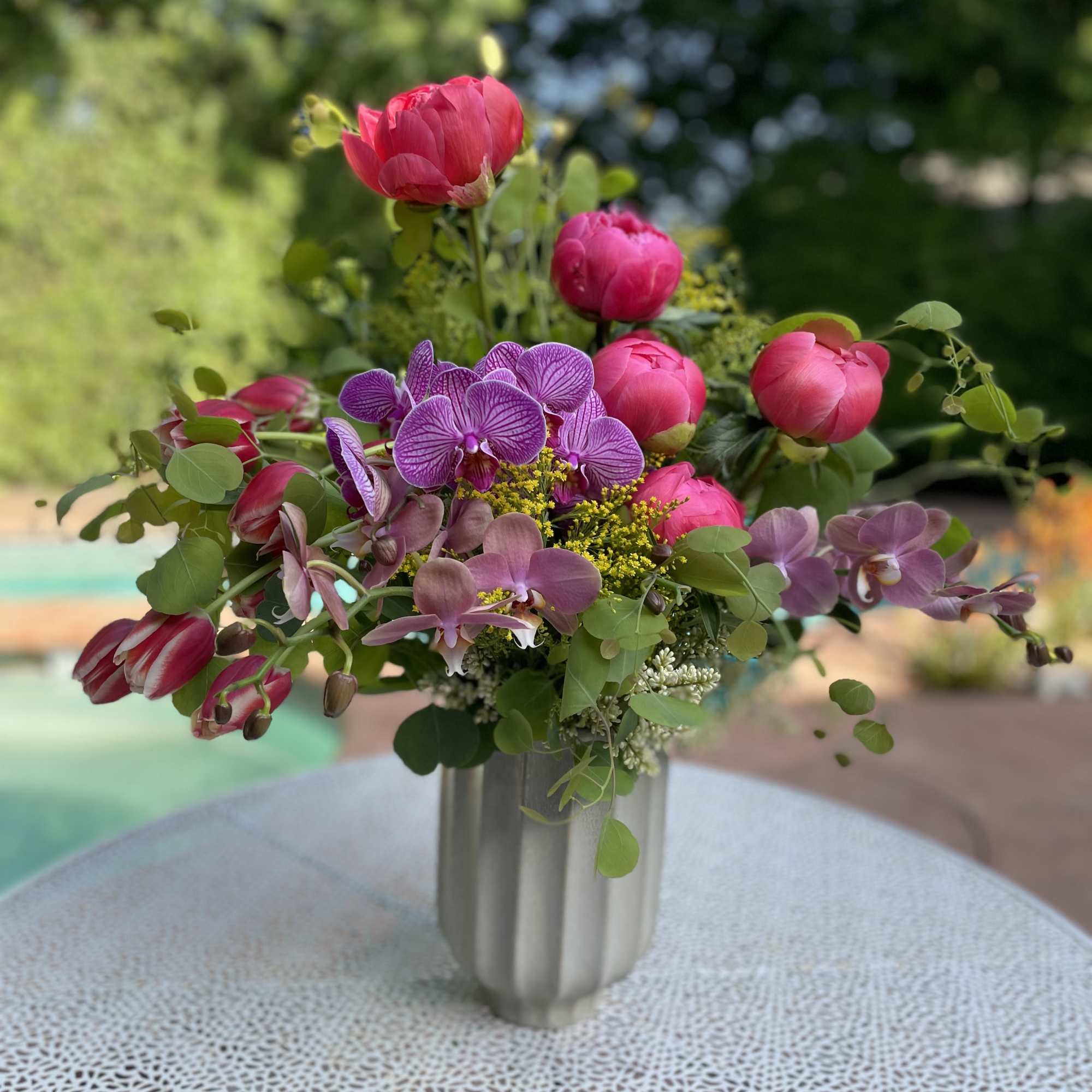 Pink and purple flowers arranged in a silver vase