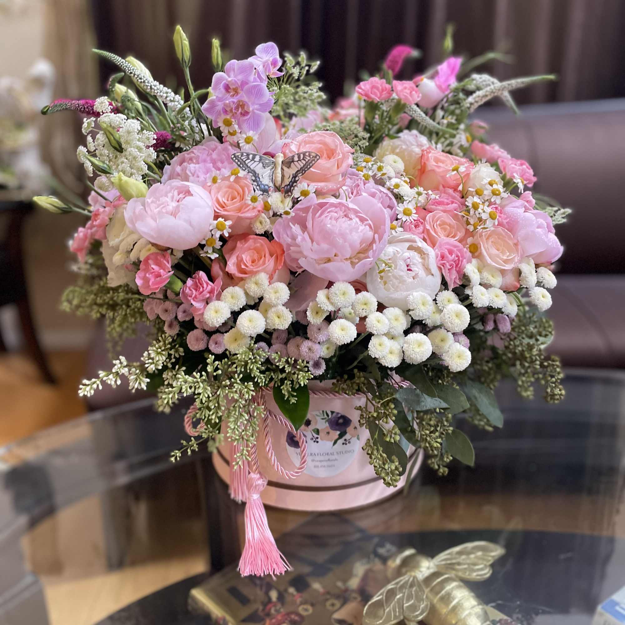 Pink mixed flower arrangement in a round hatbox with a tassel