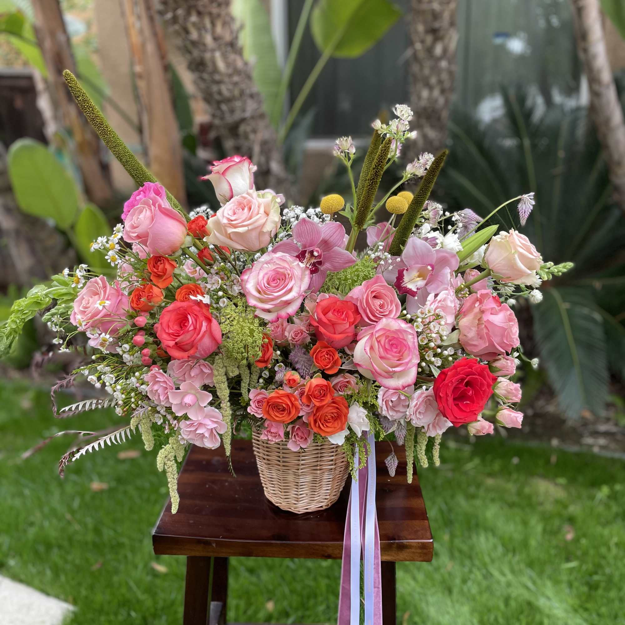 Mixed pink and coral rose arrangement in a wicker basket