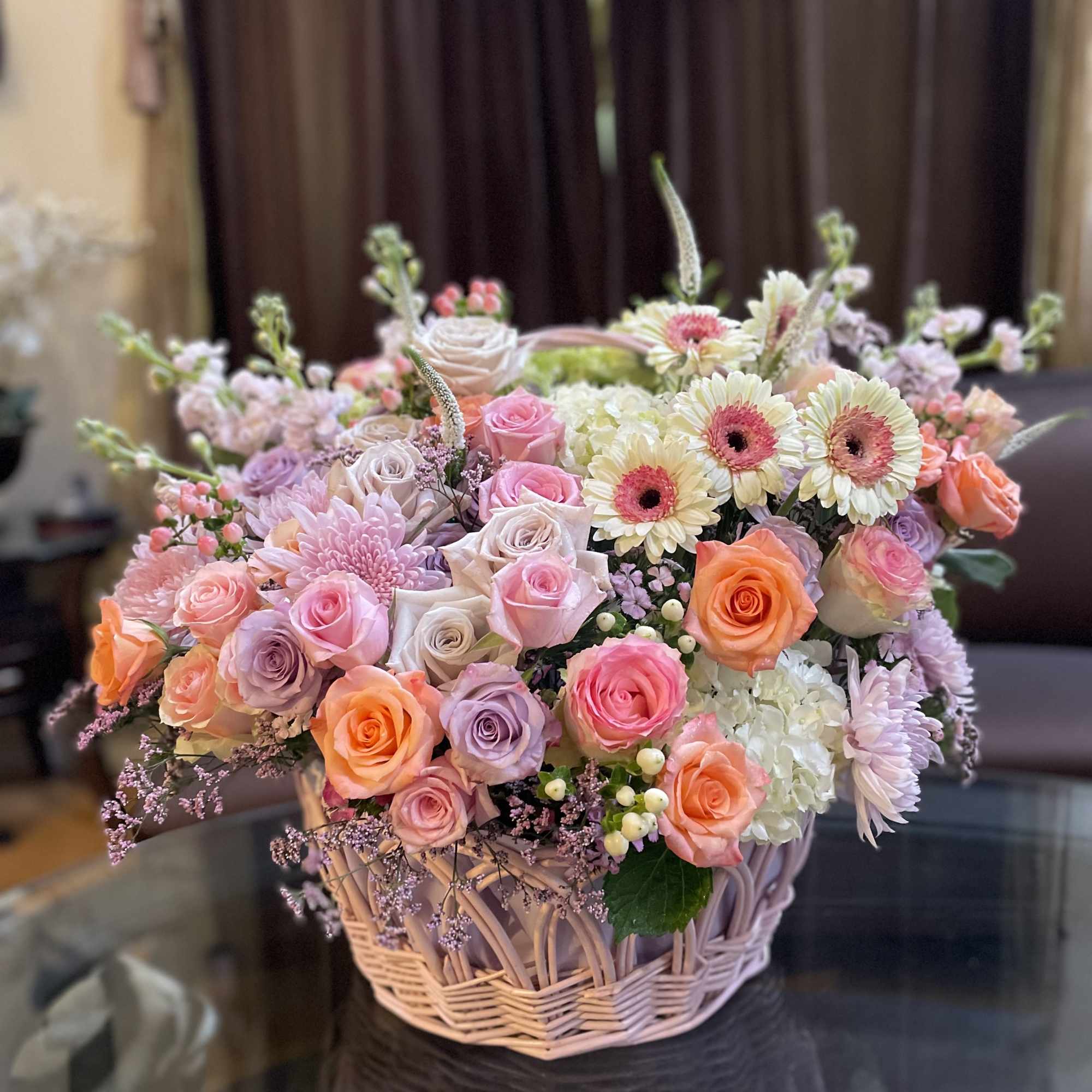 Basket arrangement of pink and peach roses with white daisies
