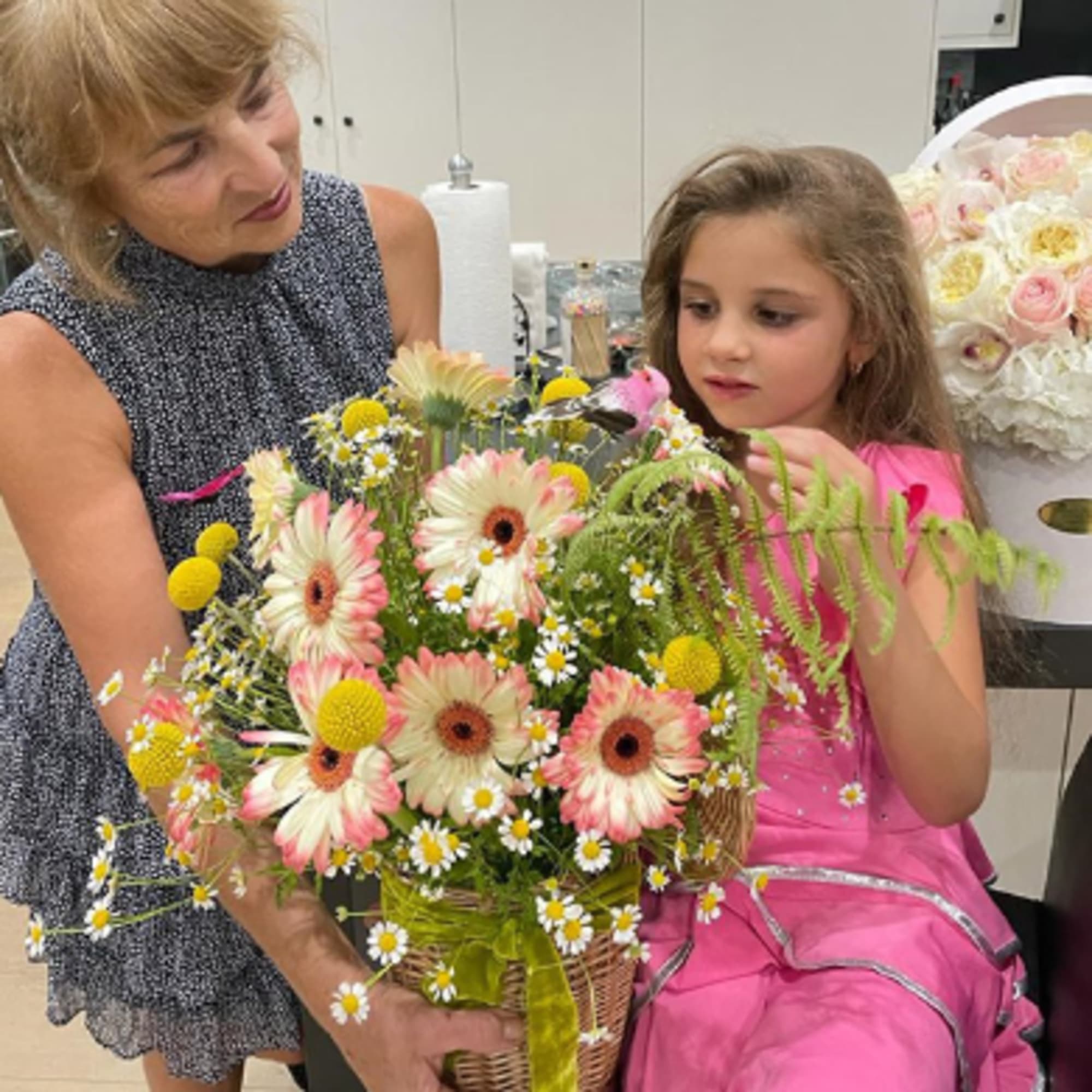 Woman and girl holding a basket of pink gerbera daisies and daisies