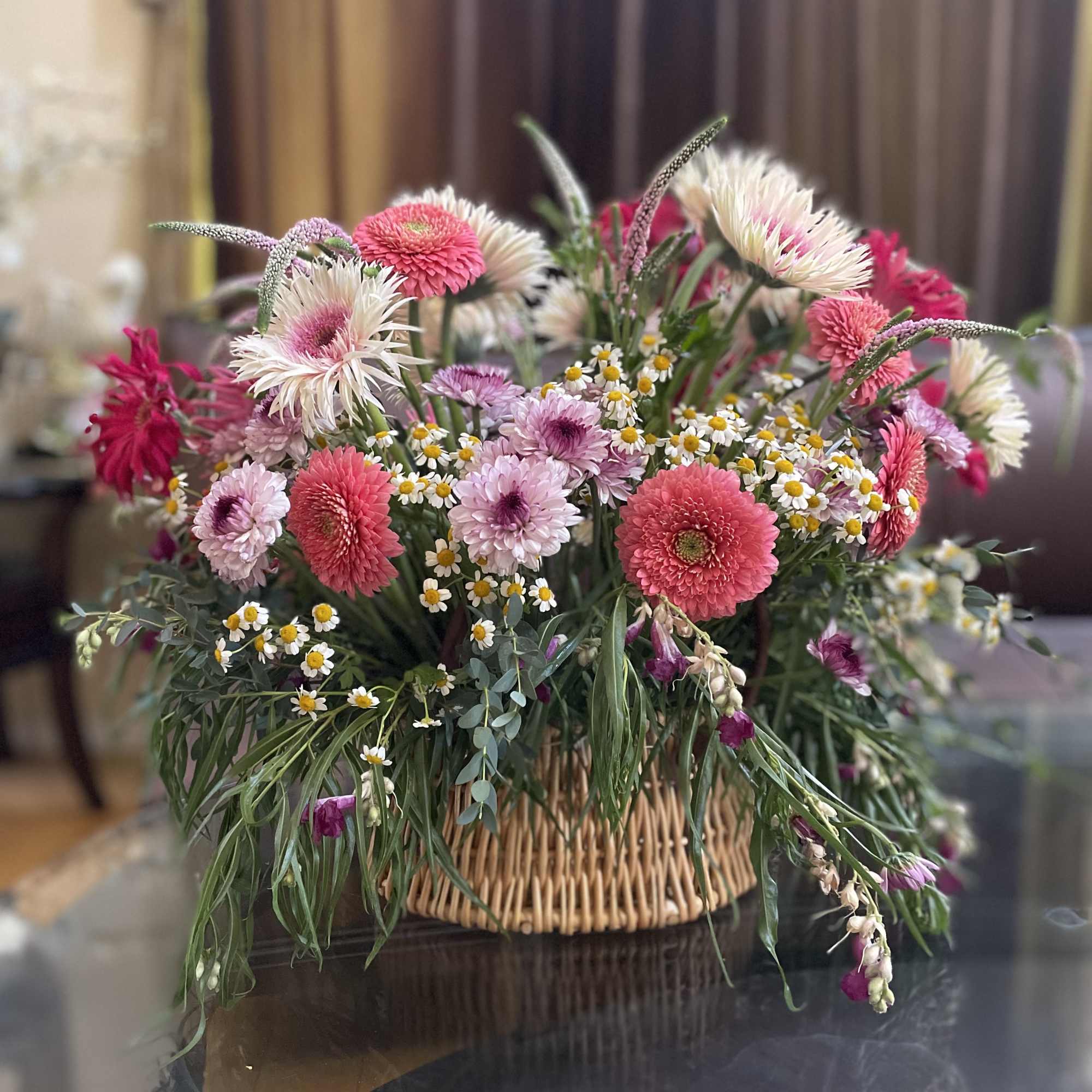 Mixed pink and white flowers arranged in a wicker basket