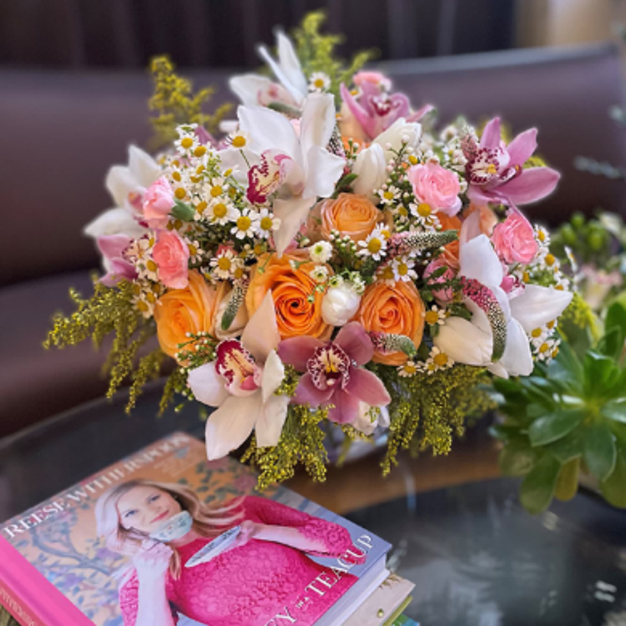Bouquet of orange roses, pink orchids, and white daisies