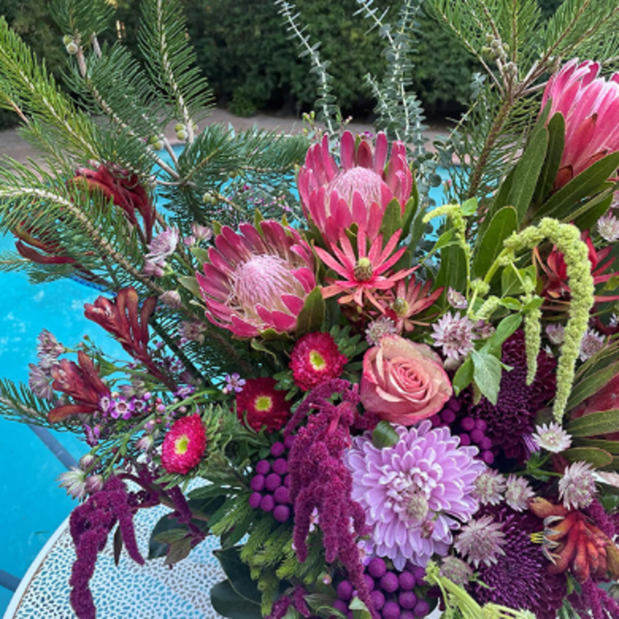 Pink and purple floral arrangement with protea and roses