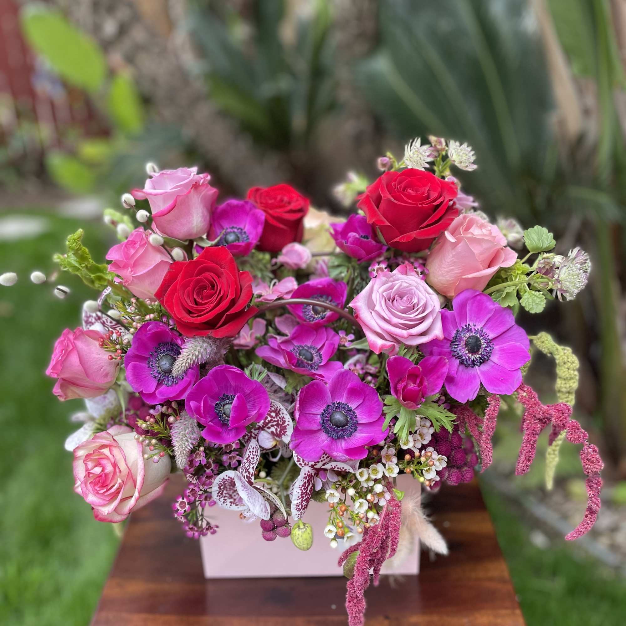 Pink and red rose bouquet with magenta anemones in a pale box