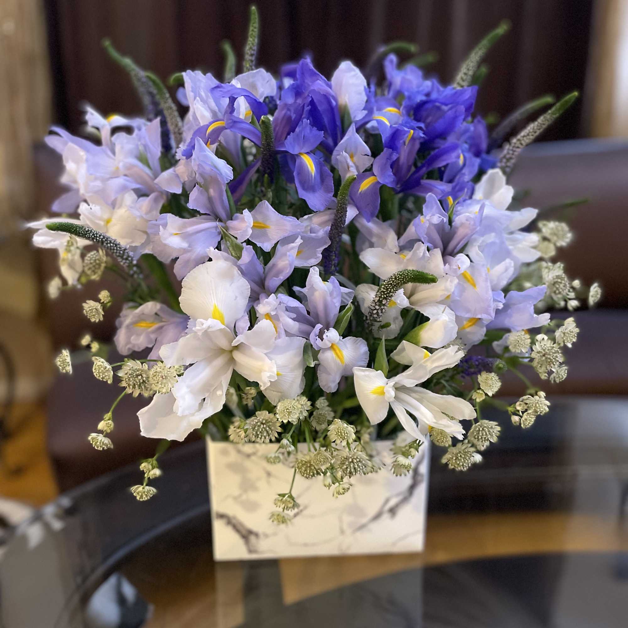 Blue and white iris arrangement in a square vase