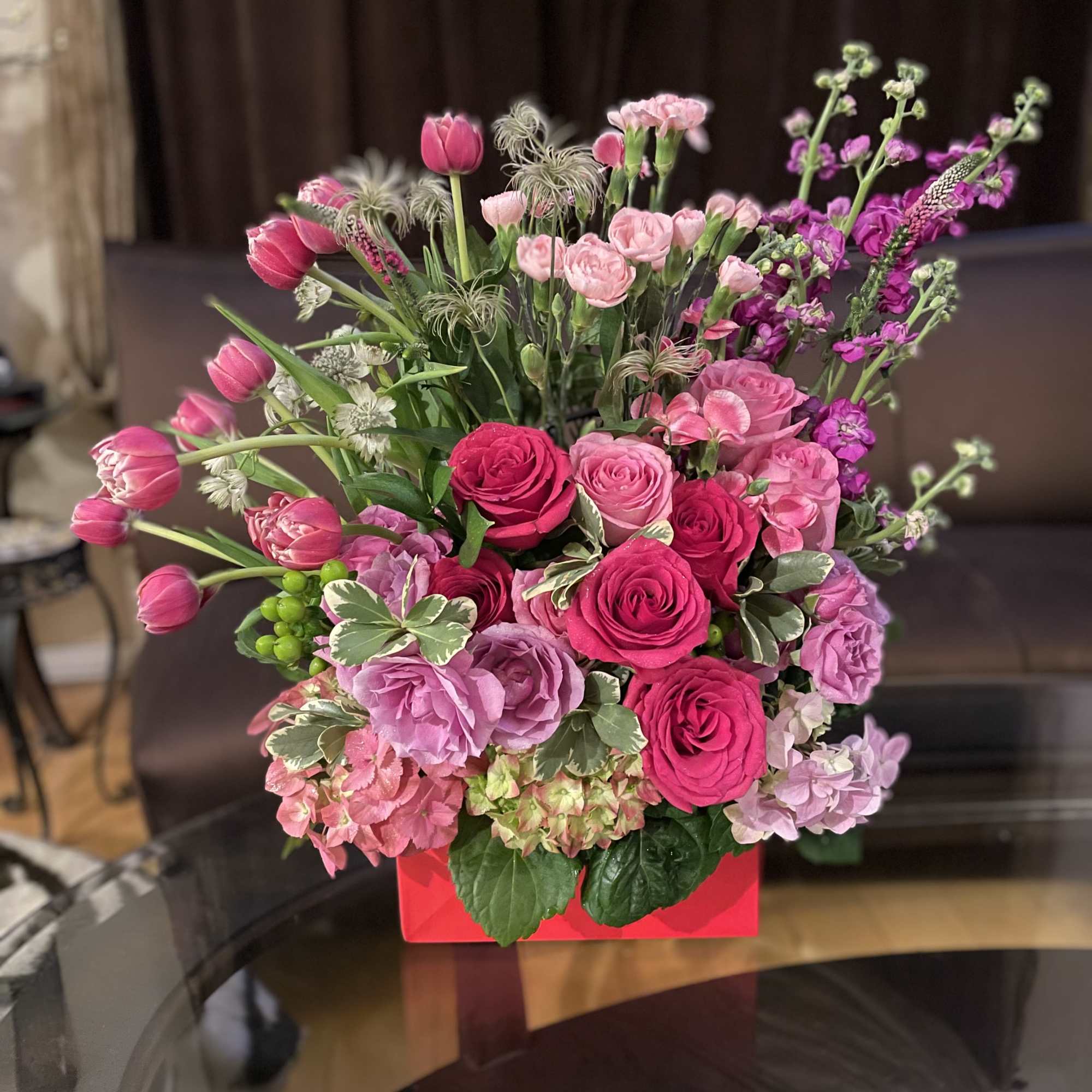 Pink and purple mixed flower arrangement in a red box