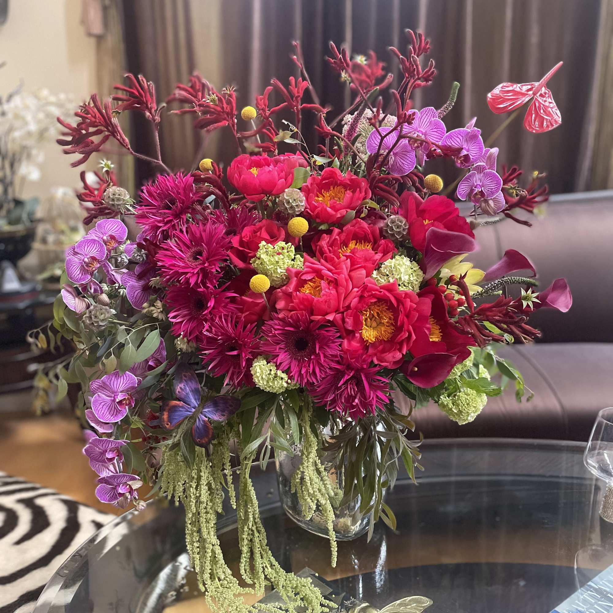 Bright pink floral arrangement in a clear glass vase with orchids and calla lilies
