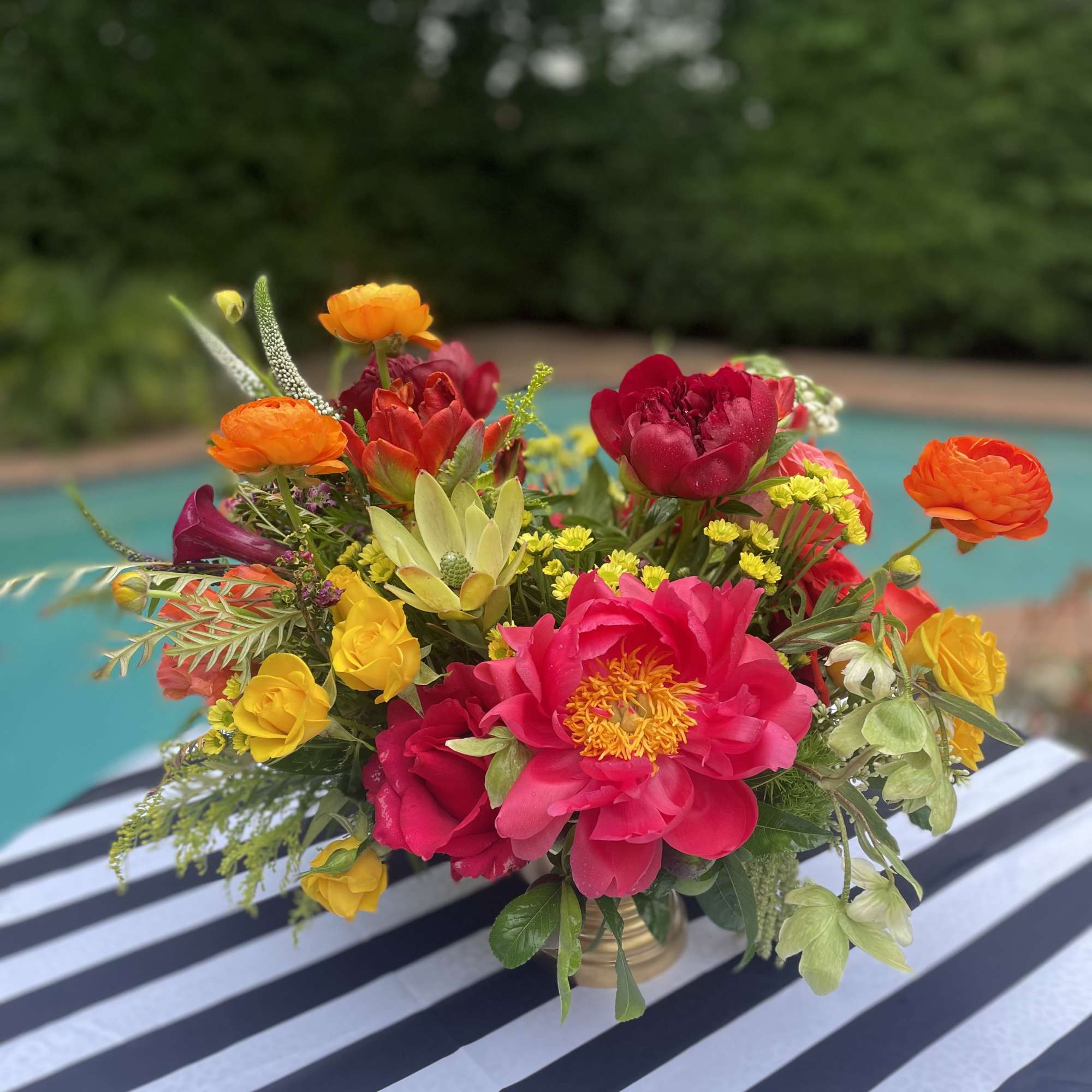 Bright mixed bouquet in a gold vase with pink, orange, and yellow blooms