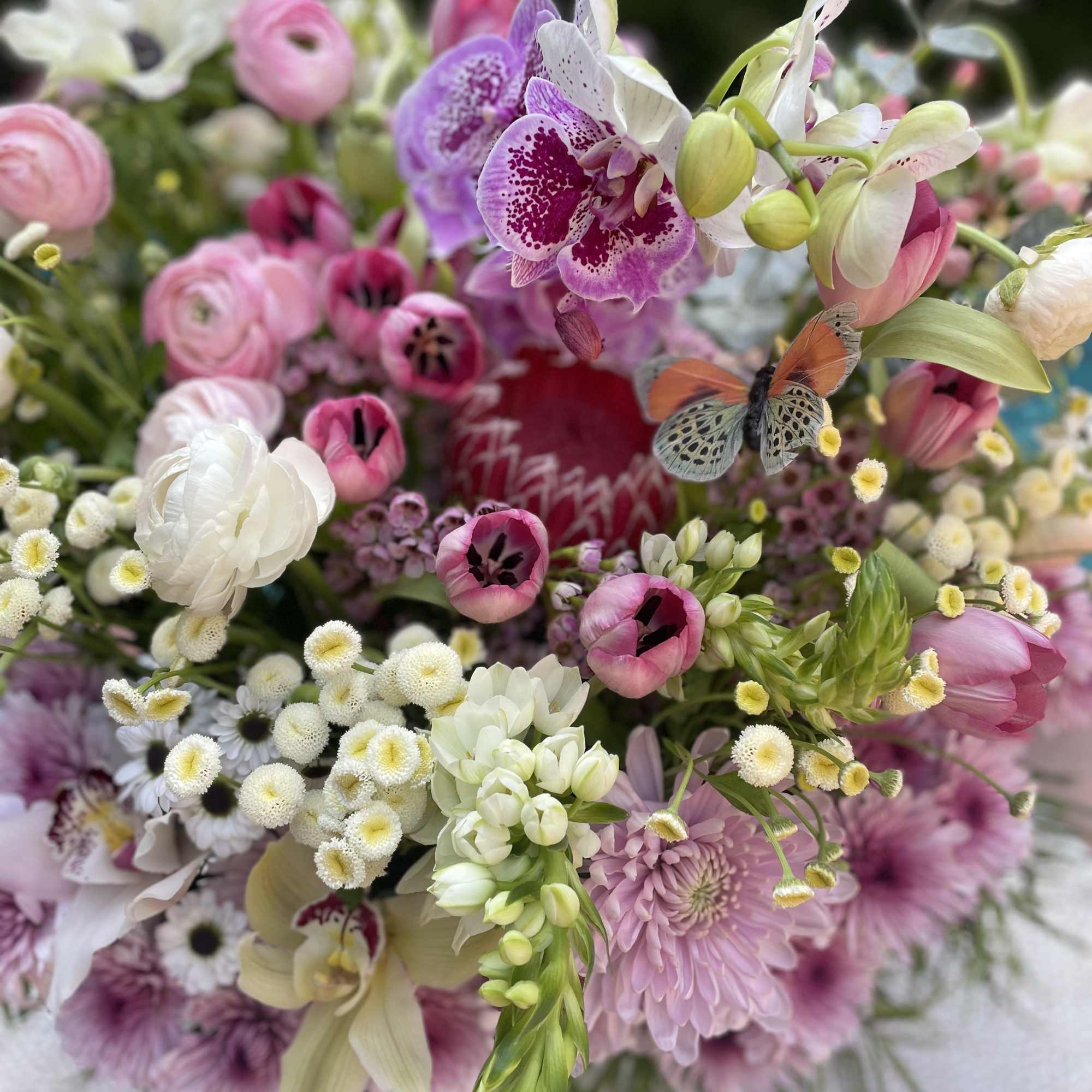 Mixed bouquet of pink, white, and purple flowers with orchids and tulips