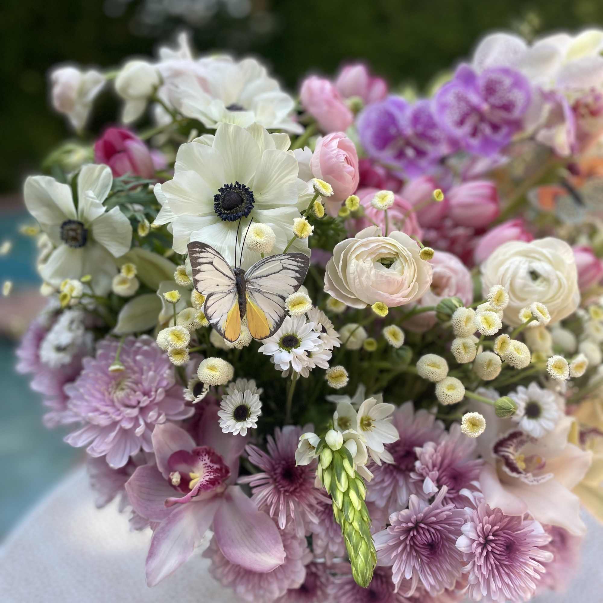 Bouquet of white, pink, and lavender flowers with a butterfly accent