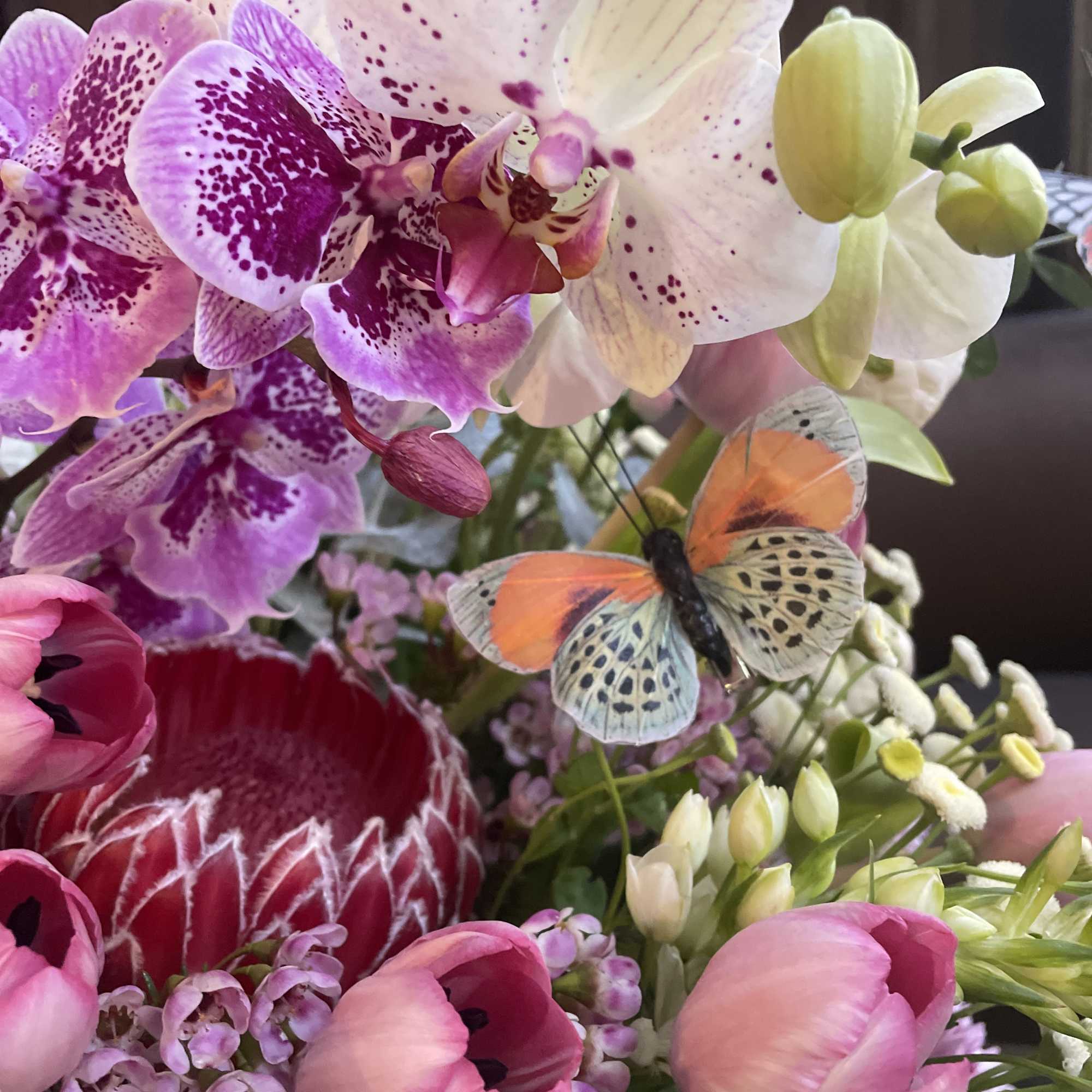 Bouquet of orchids, pink tulips, and a butterfly decoration