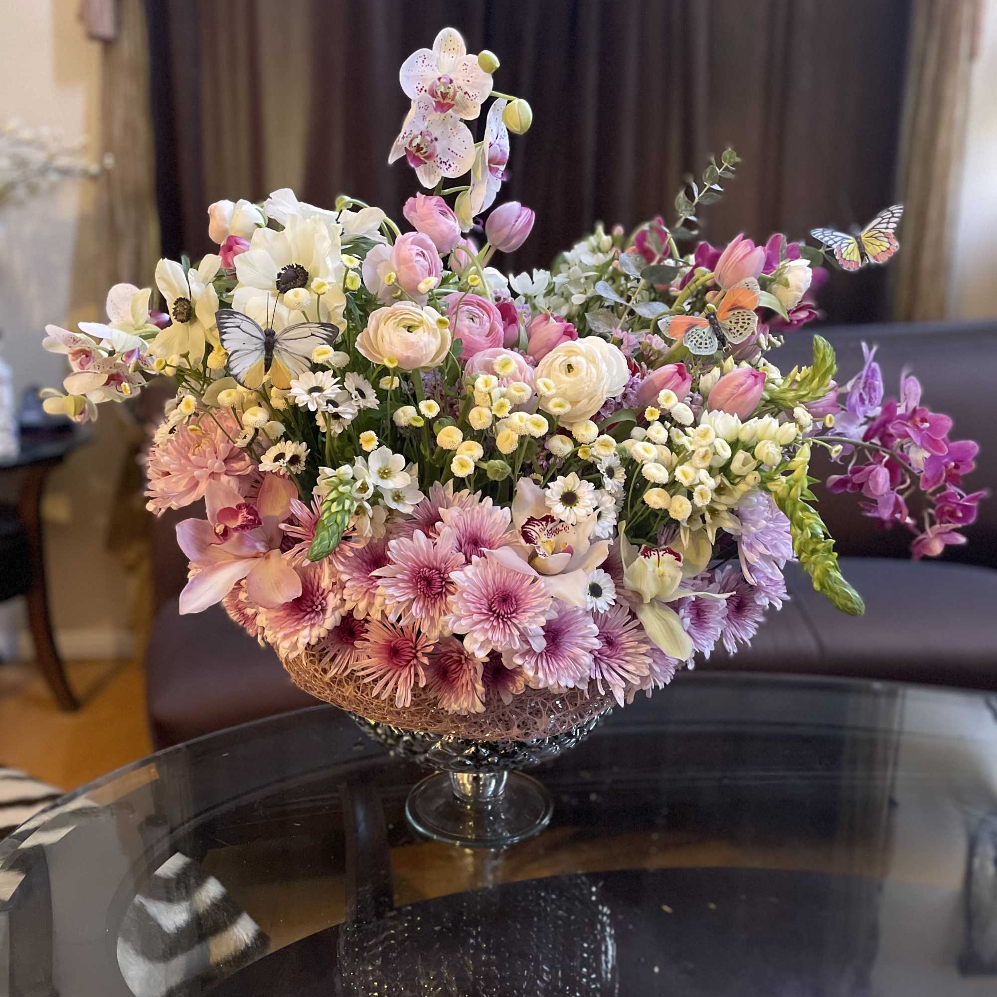 Mixed pastel flower arrangement in a glass pedestal bowl
