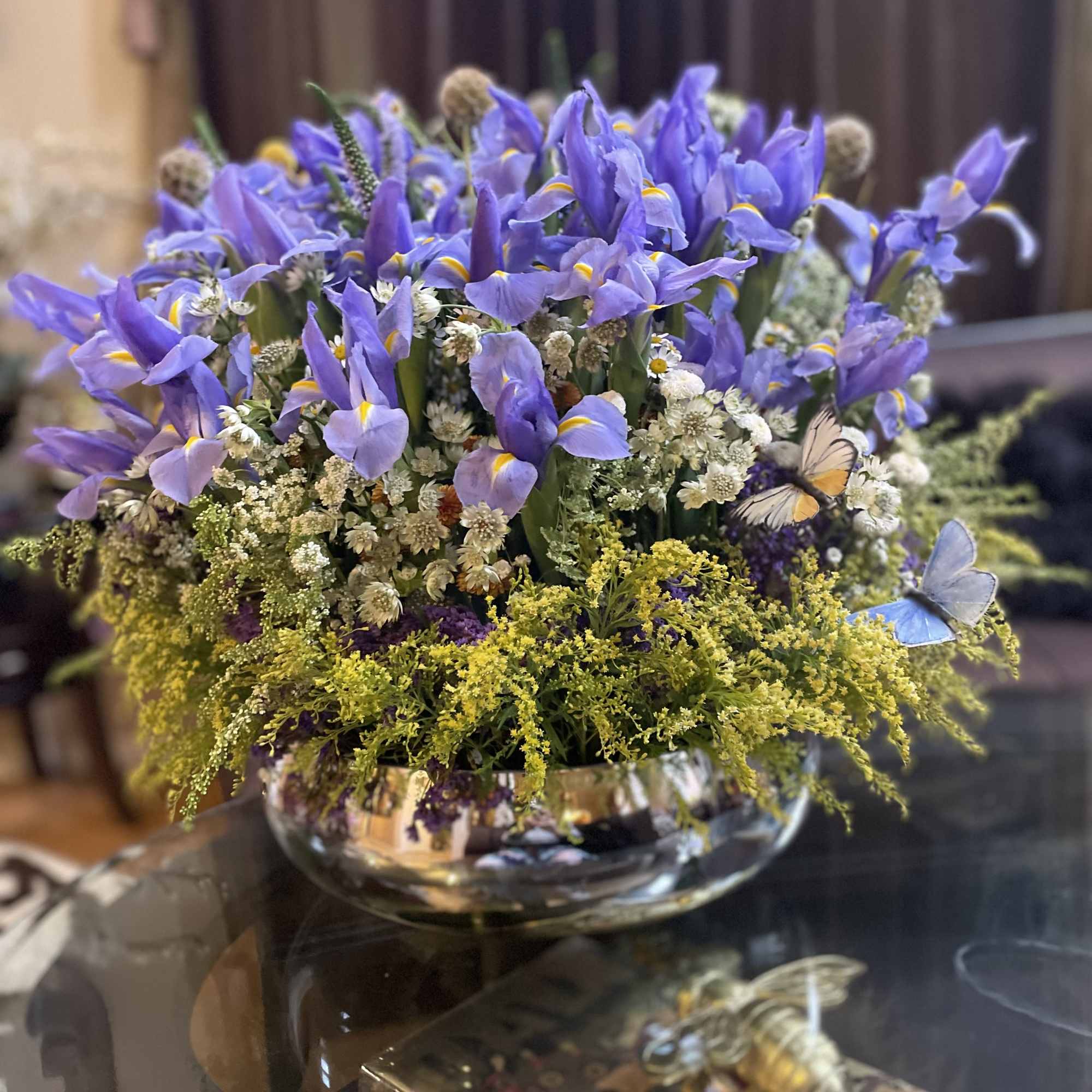Purple iris arrangement in a low glass bowl with small white filler flowers